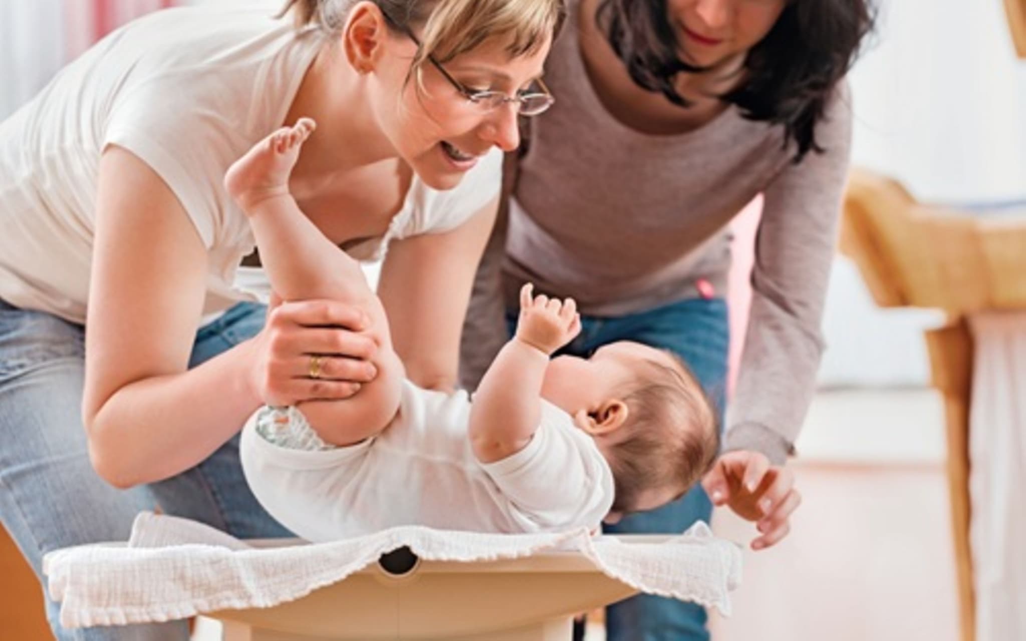 Frau mit Kleinkind auf Waage