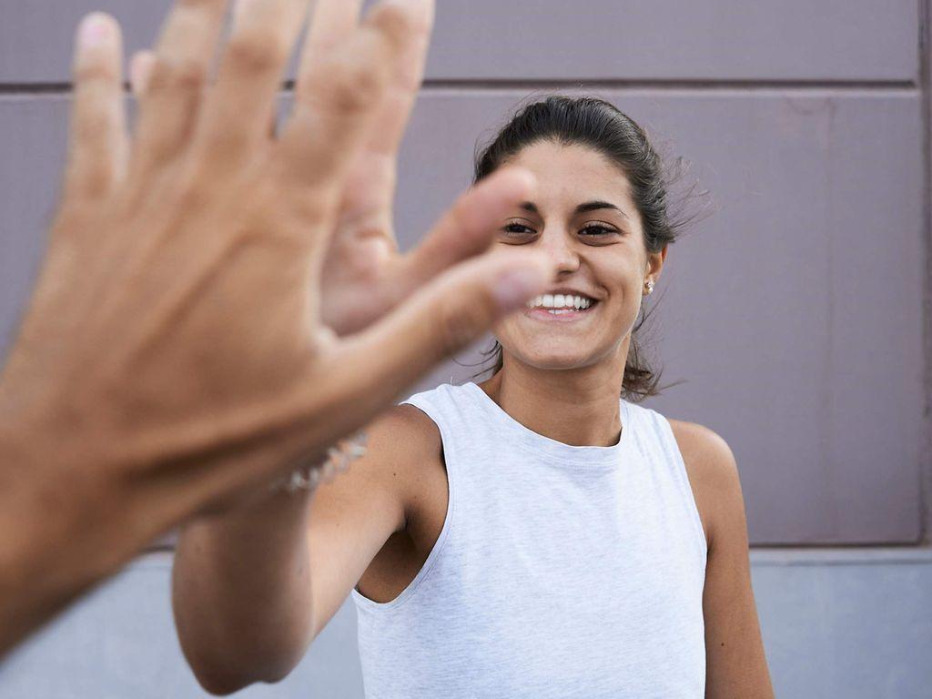 Vorsorgeuntersuchungen für Frauen: Frau klatscht mit einer Hand eine andere Hand im Vordergrund ab.