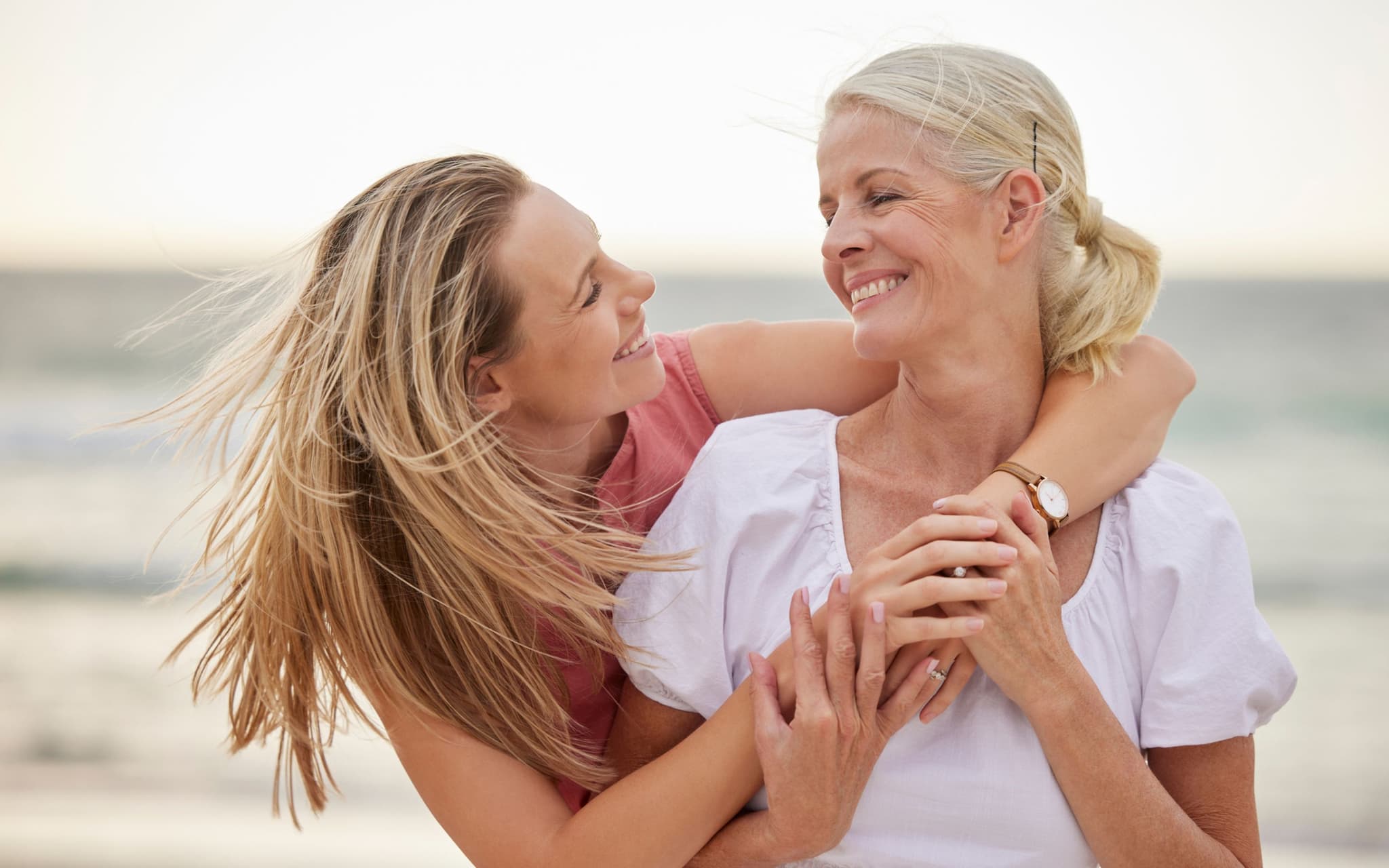 Vulva-Entwicklung: Eine Mutter umarmt ihre Tochter am Strand