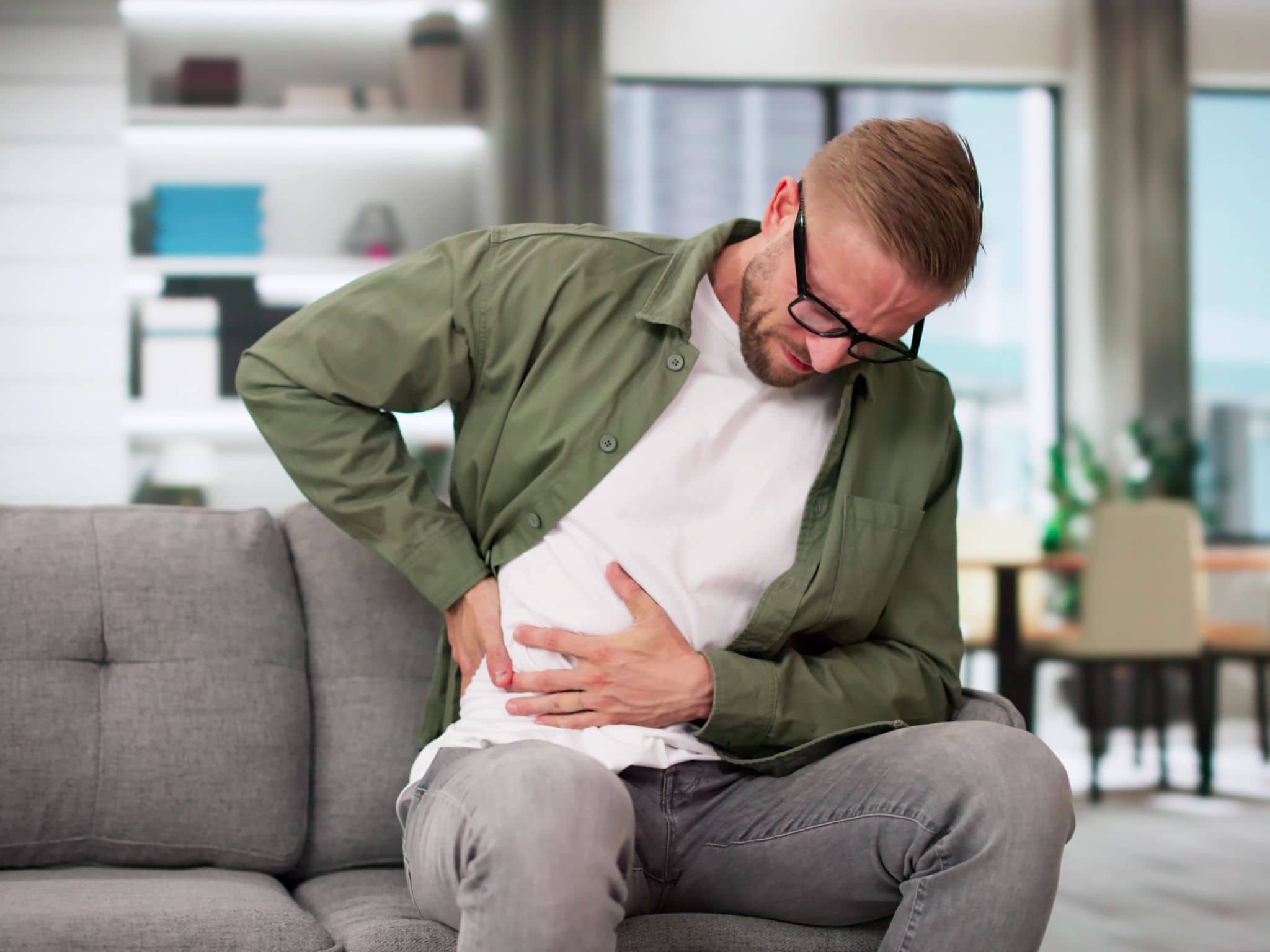 Harnwegsinfekt: Junger Mann hat Schmerzen auf Sofa
