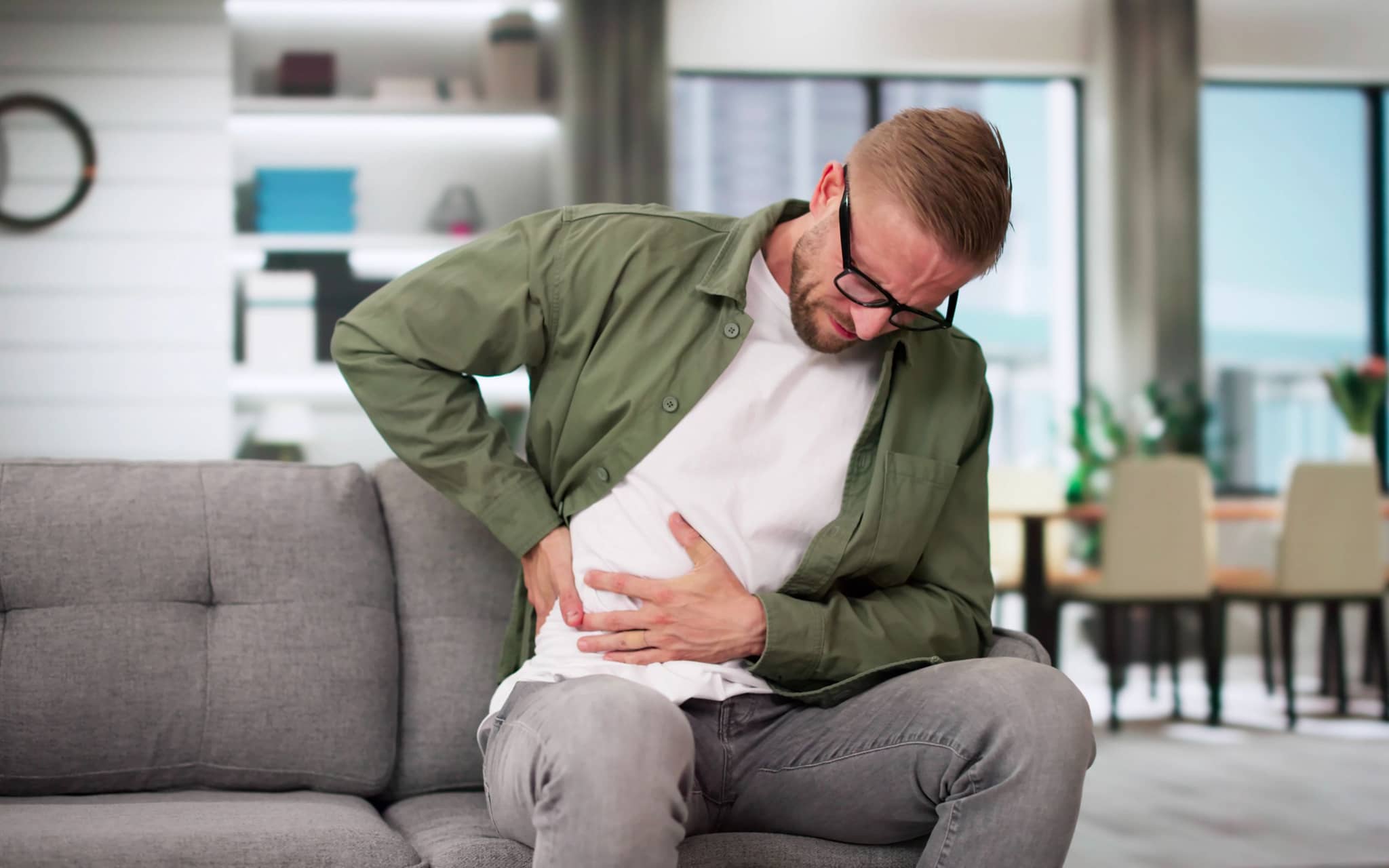 Harnwegsinfekt: Junger Mann hat Schmerzen auf Sofa