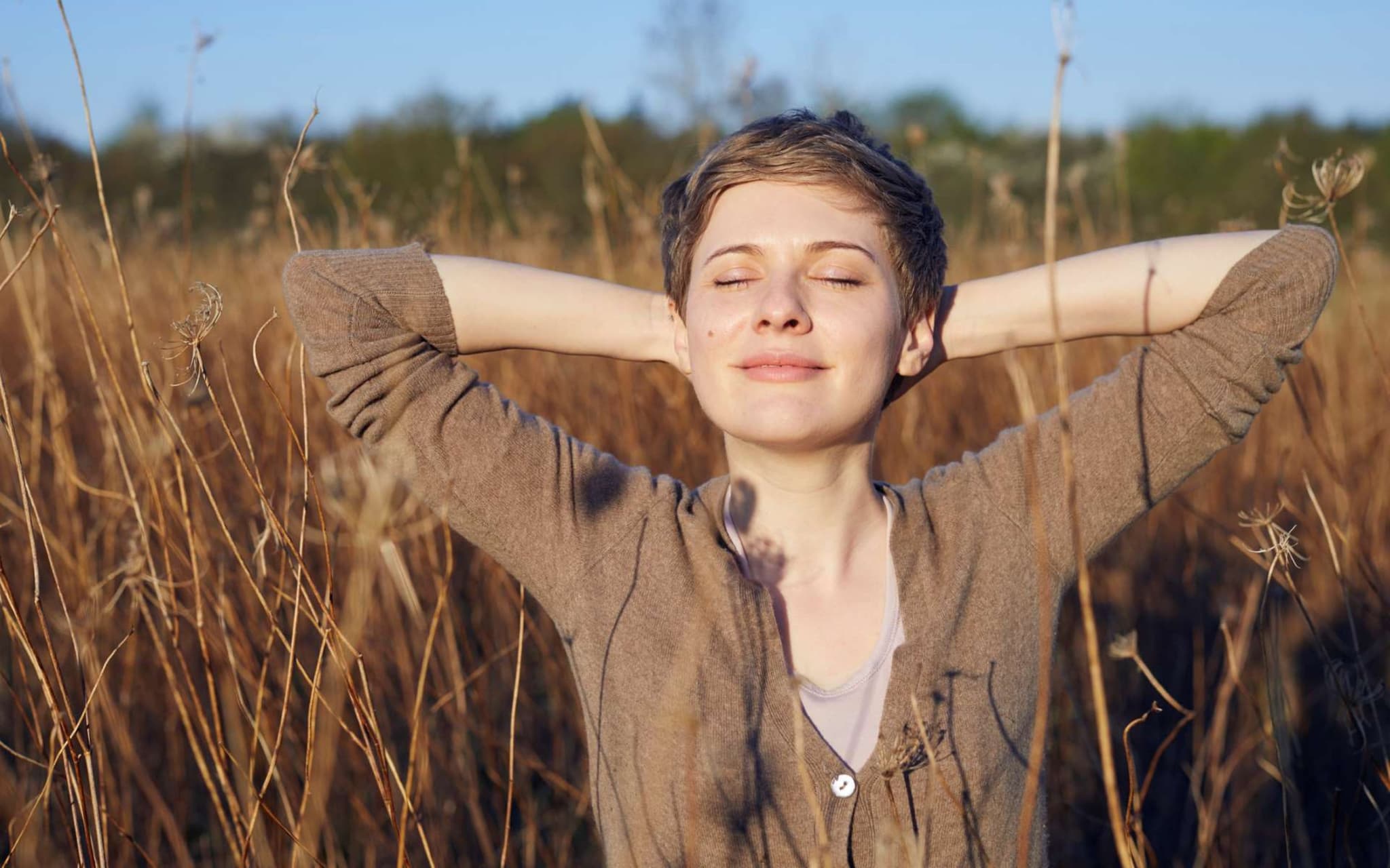Abendritual: Eine junge Frau steht mit geschlossenen Augen in einem Kornfeld.