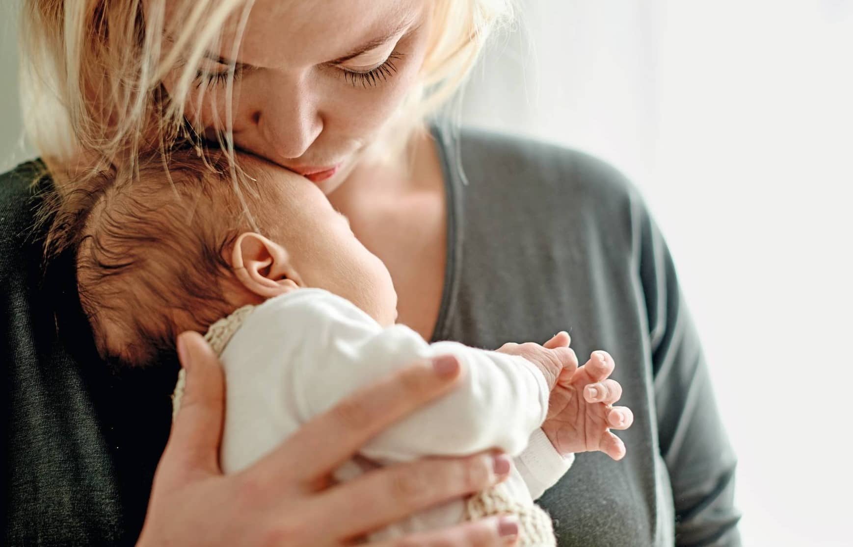 Eine Mutter küsst ihr Baby, das dank Kinderwunschbehandlung zur Welt gekommen ist.