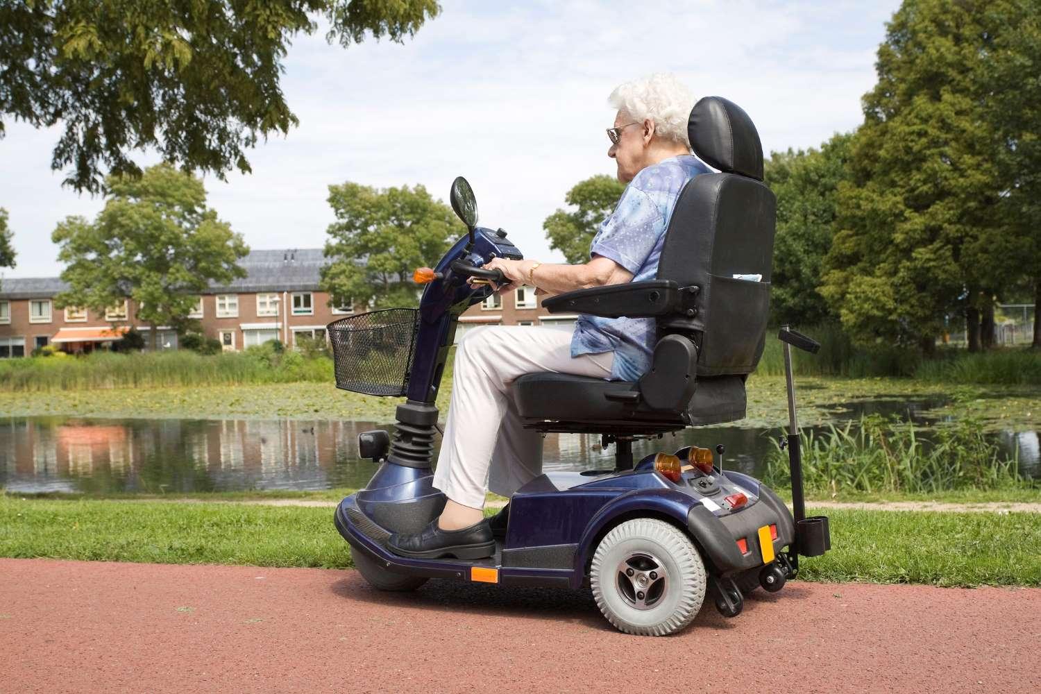 Krankenfahrzeuge: Ältere Frau fährt mit einem Elektromobil an einem Fluss entlang.