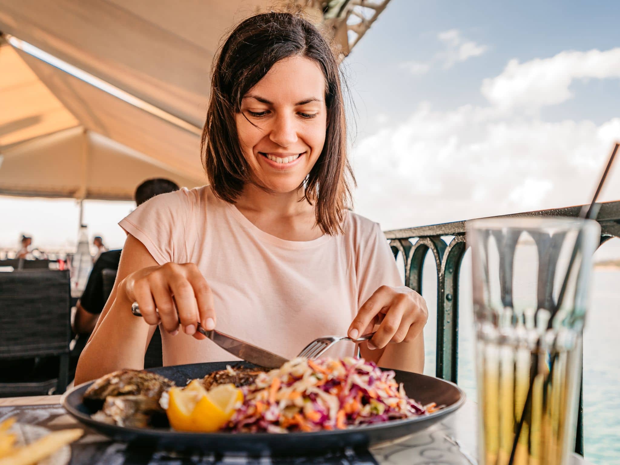 Pescetarier: Frau isst eine Fischmahlzeit am Meer.