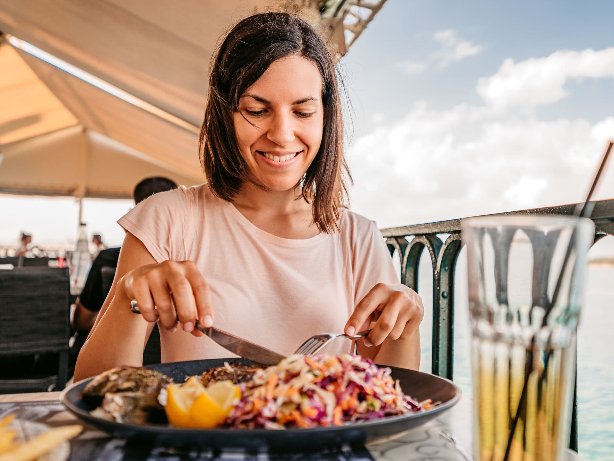 Pescetarier: Frau isst eine Fischmahlzeit am Meer.
