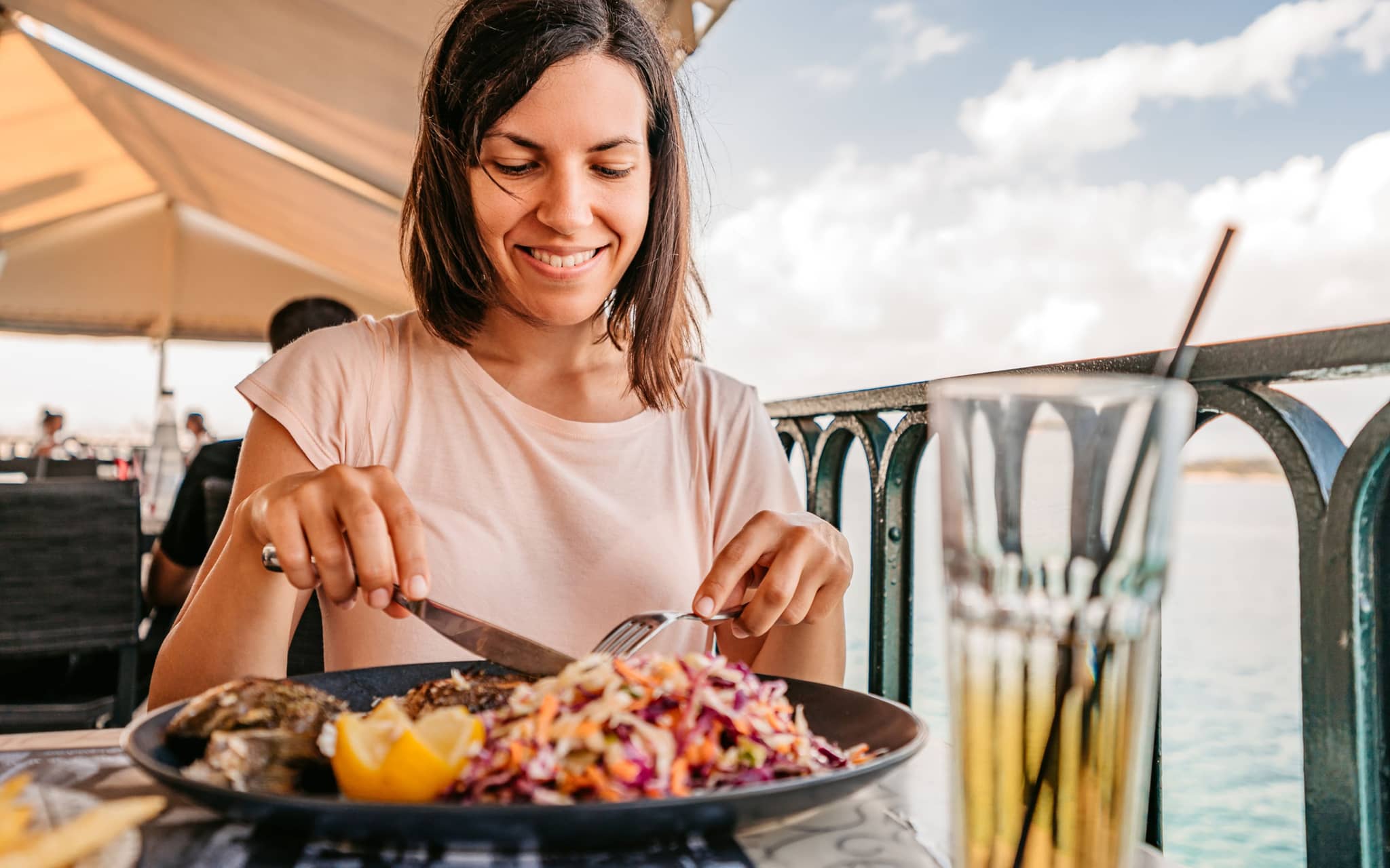 Pescetarier: Frau isst eine Fischmahlzeit am Meer.