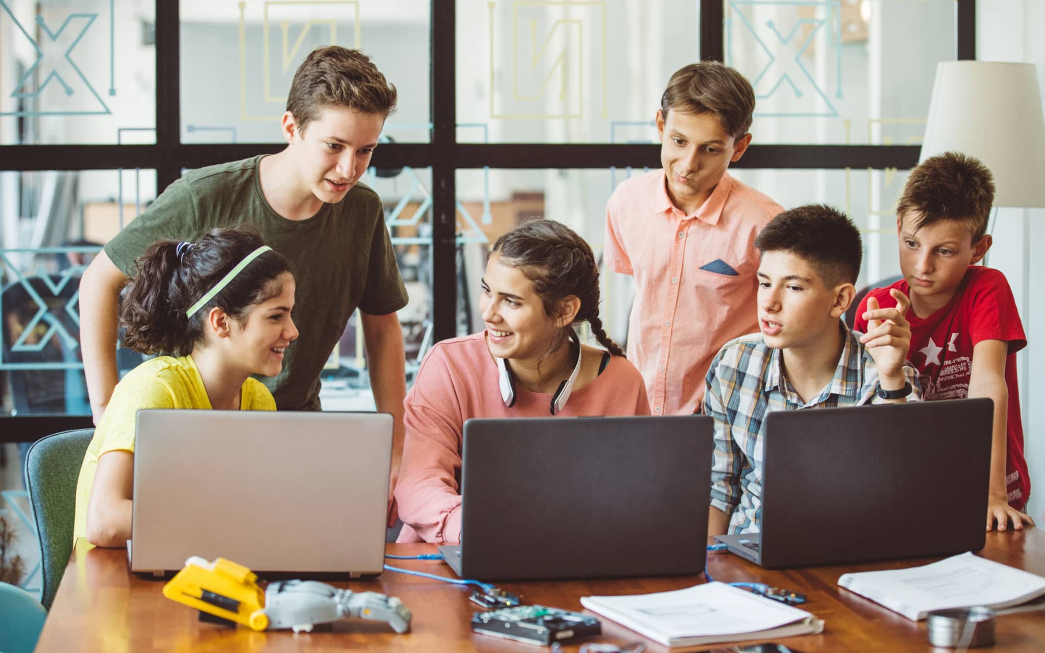 Bild: Eine Gruppe von Jugendlichen sitzt um Computer herum und lernt.