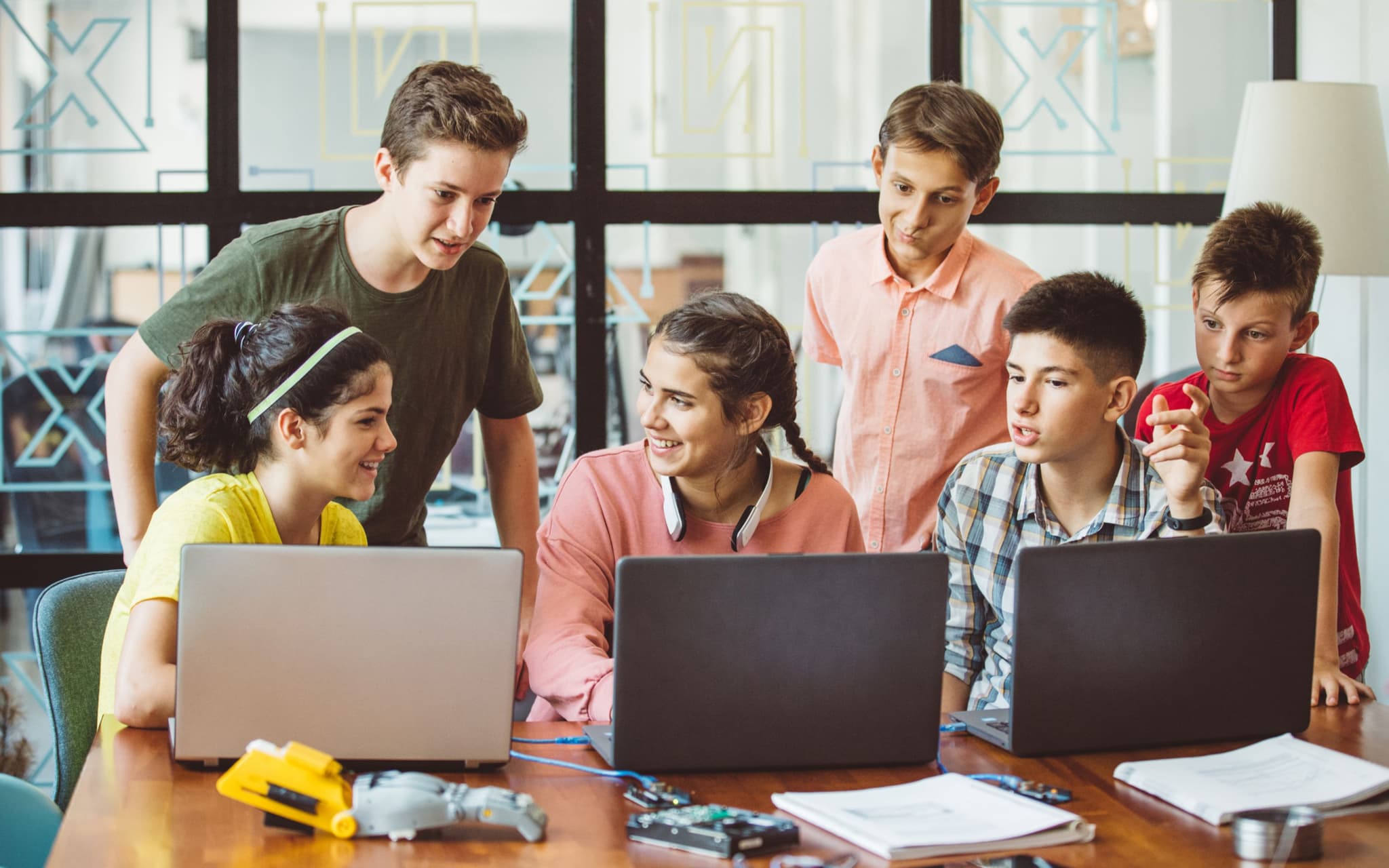 Bild: Eine Gruppe von Jugendlichen sitzt um Computer herum und lernt.