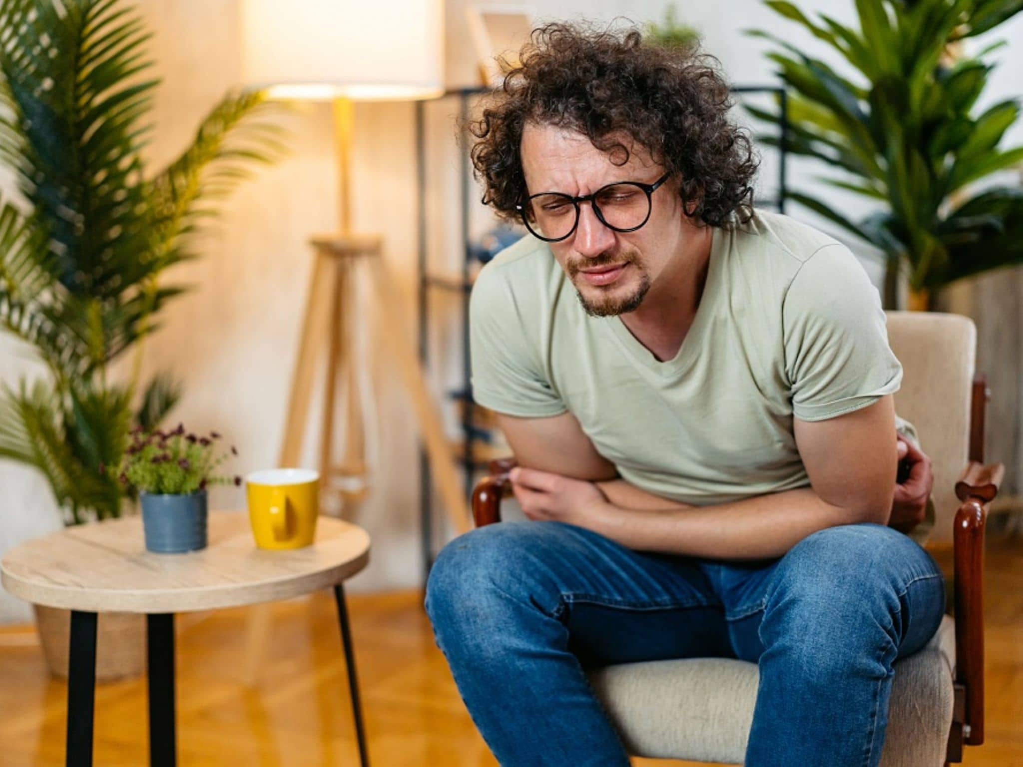 Ernährung bei Verstopfung: Ein Mann sitzt im Sessel und hält sich den schmerzenden Bauch.