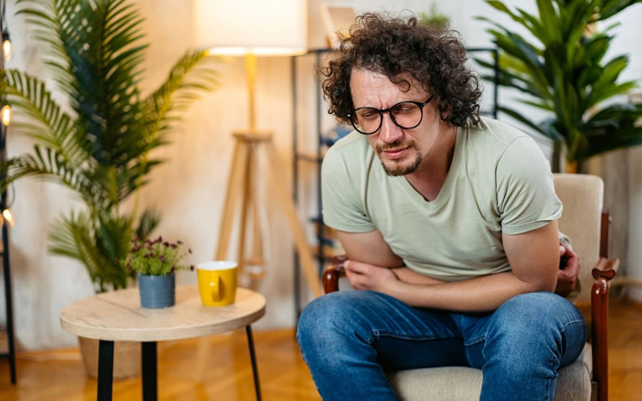 Ernährung bei Verstopfung: Ein Mann sitzt im Sessel und hält sich den schmerzenden Bauch.