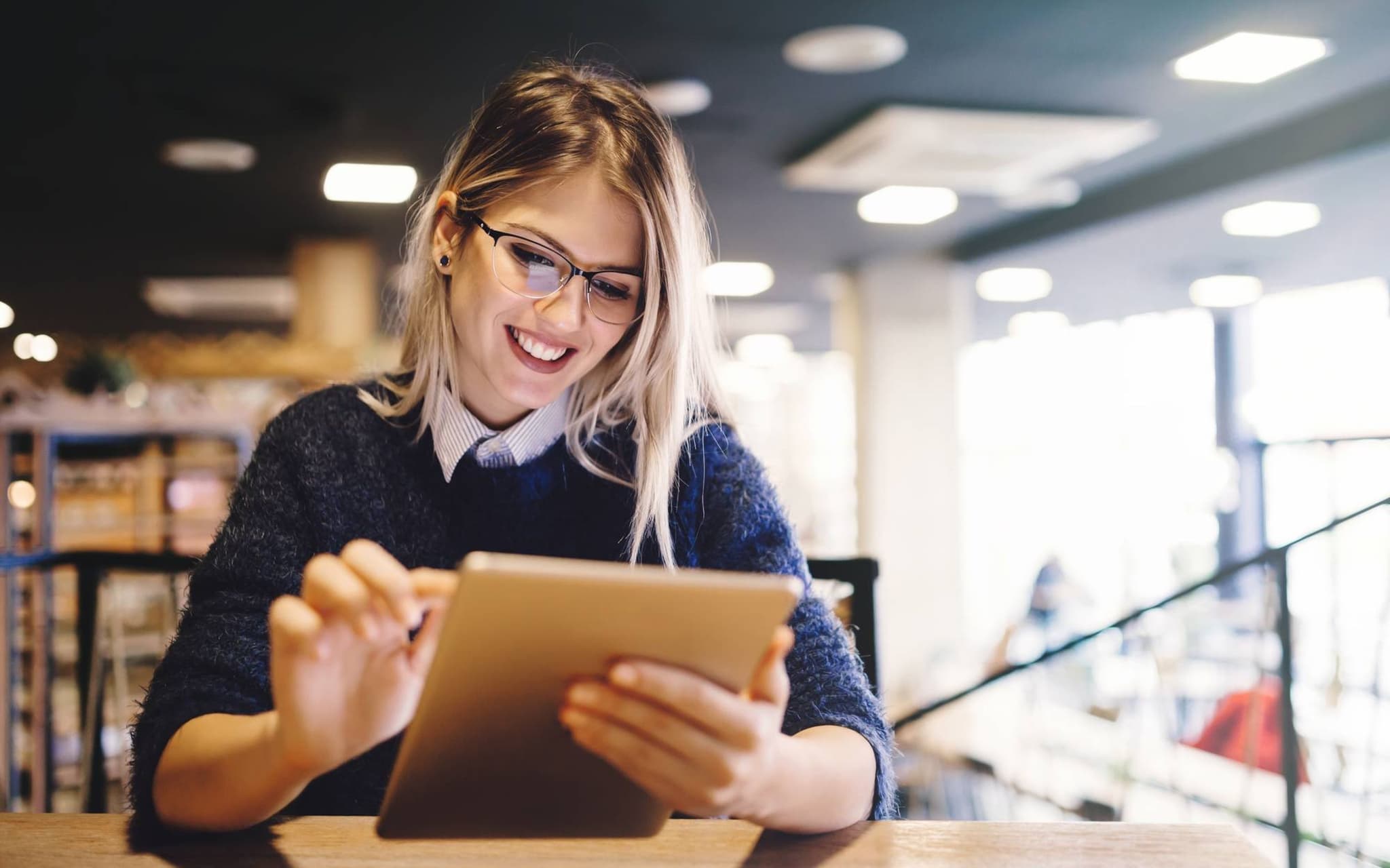 Bild: Junge Frau lächelt während sie sich auf dem Tablet die Angebote der DAK anschaut.