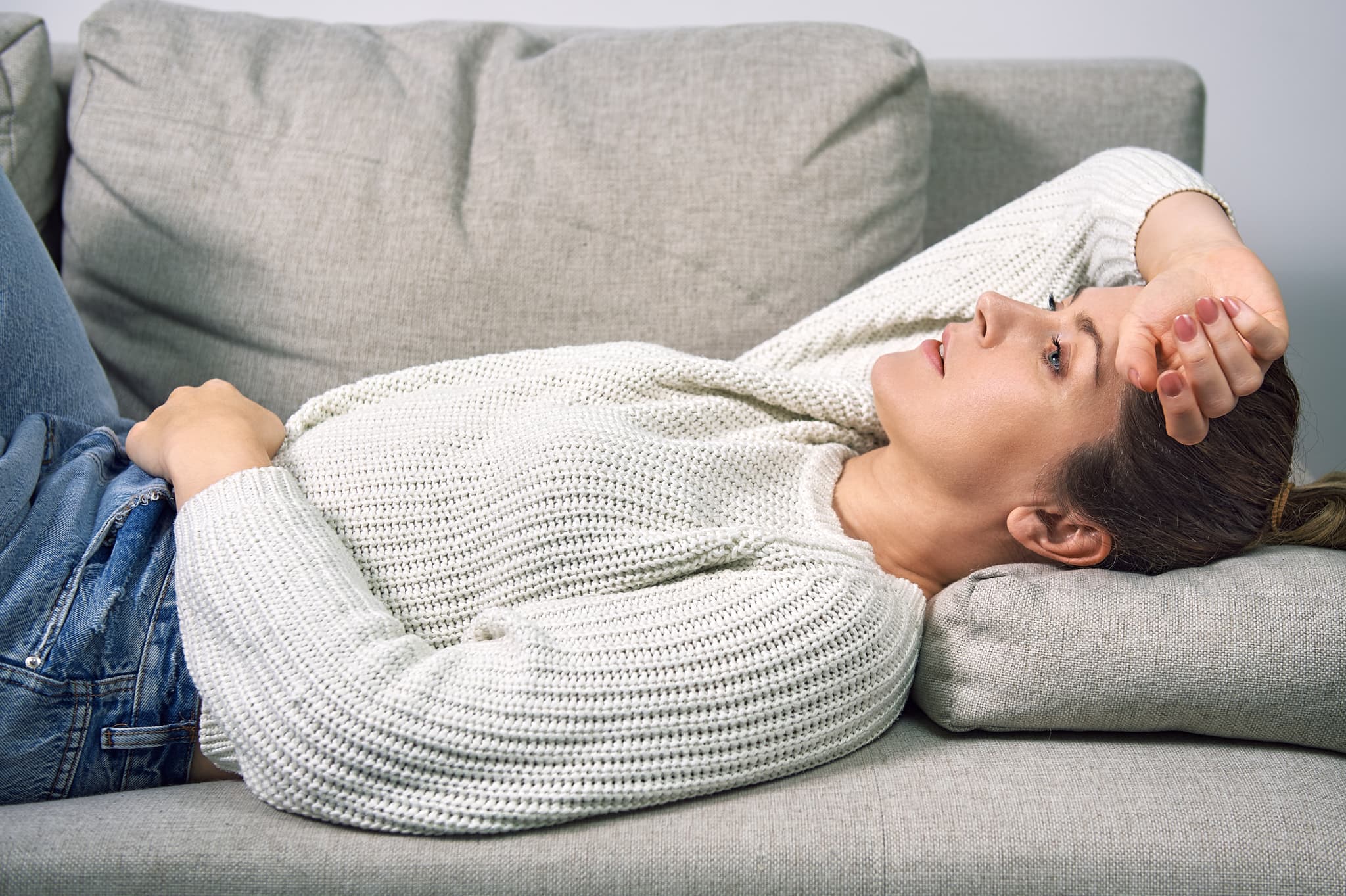 Frau mit Übelkeit liegt auf dem Sofa