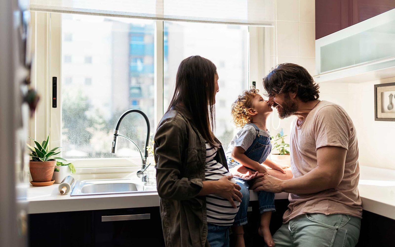 Zytomegalie-Test: Mann und schwangere Frau stehen in einer Küche und spielen mit kleinem Jungen.