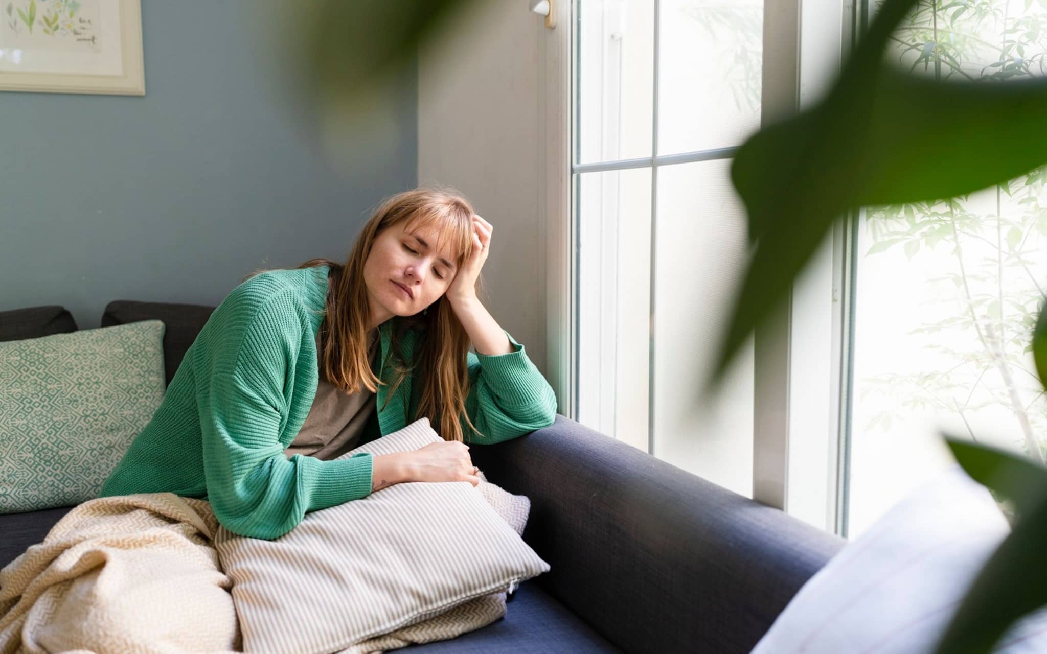 Junge Frau ruht sich auf der Couch aus, weil sie Übelkeit durch Stress empfindet.