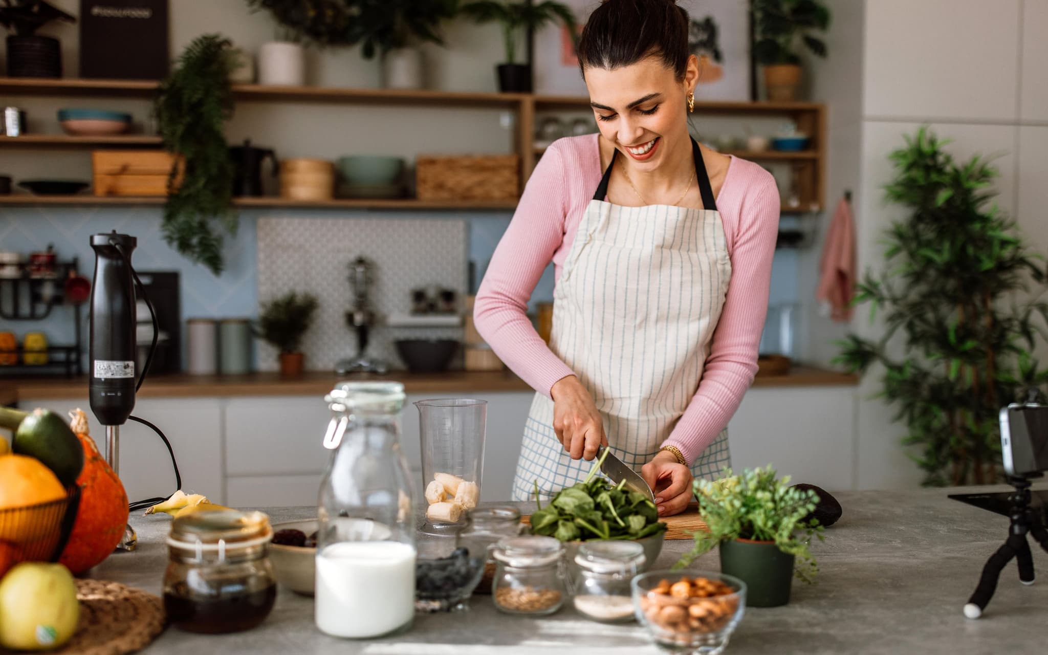 Vitamin E: Eine Frau steht in der Küche und bereitet sich eine gesunde Mahlzeit zu