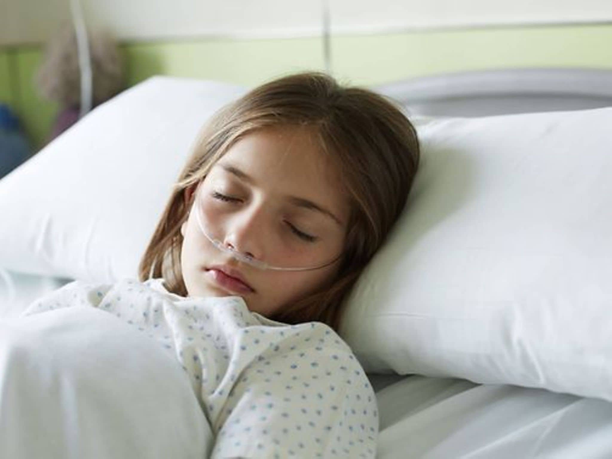 Leukämie bei Kindern: Schlafendes Mädchen mit Sauerstoffschlauch im Krankenhausbett.