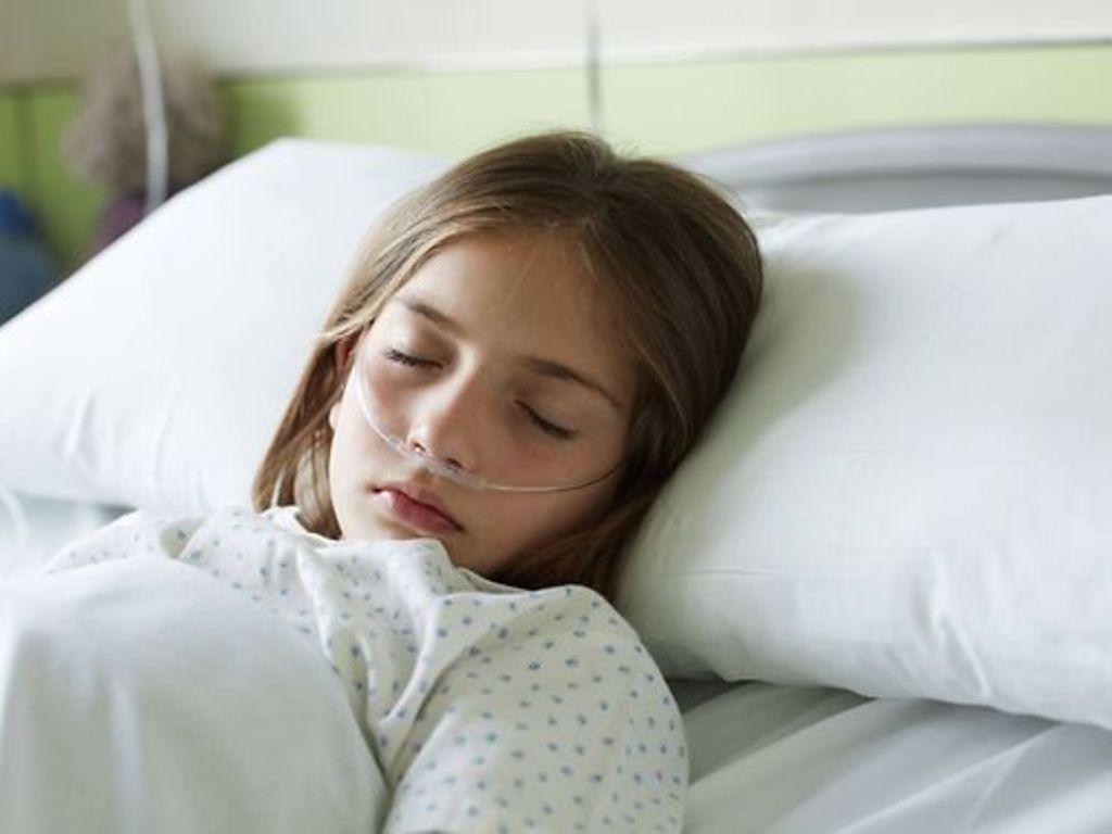 Leukämie bei Kindern: Schlafendes Mädchen mit Sauerstoffschlauch im Krankenhausbett.