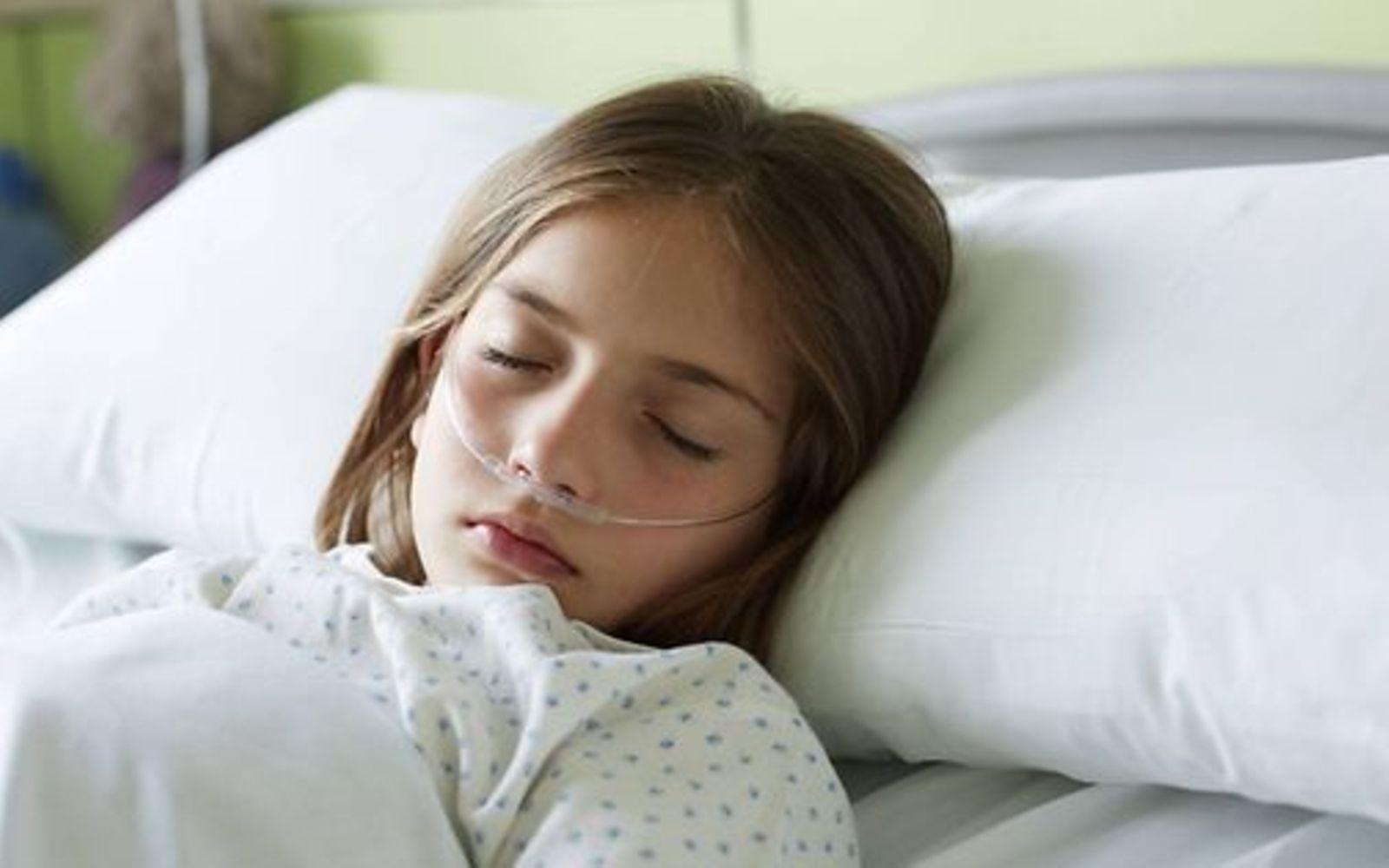 Leukämie bei Kindern: Schlafendes Mädchen mit Sauerstoffschlauch im Krankenhausbett.