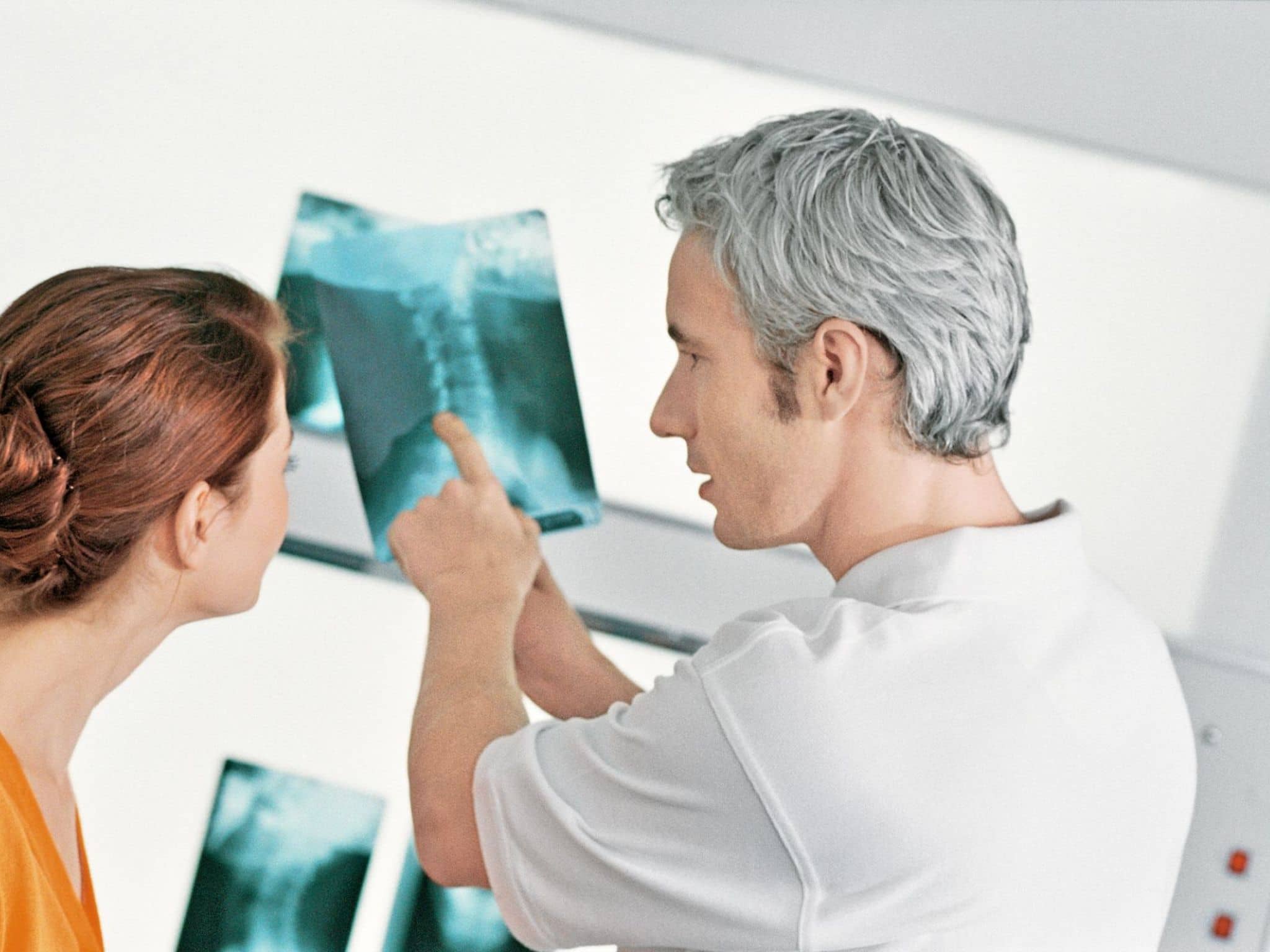 Arzt erklärt einer Patientin das Röntgenbild, das sie später in ihrer elektronischen Patientenakte finden wird.