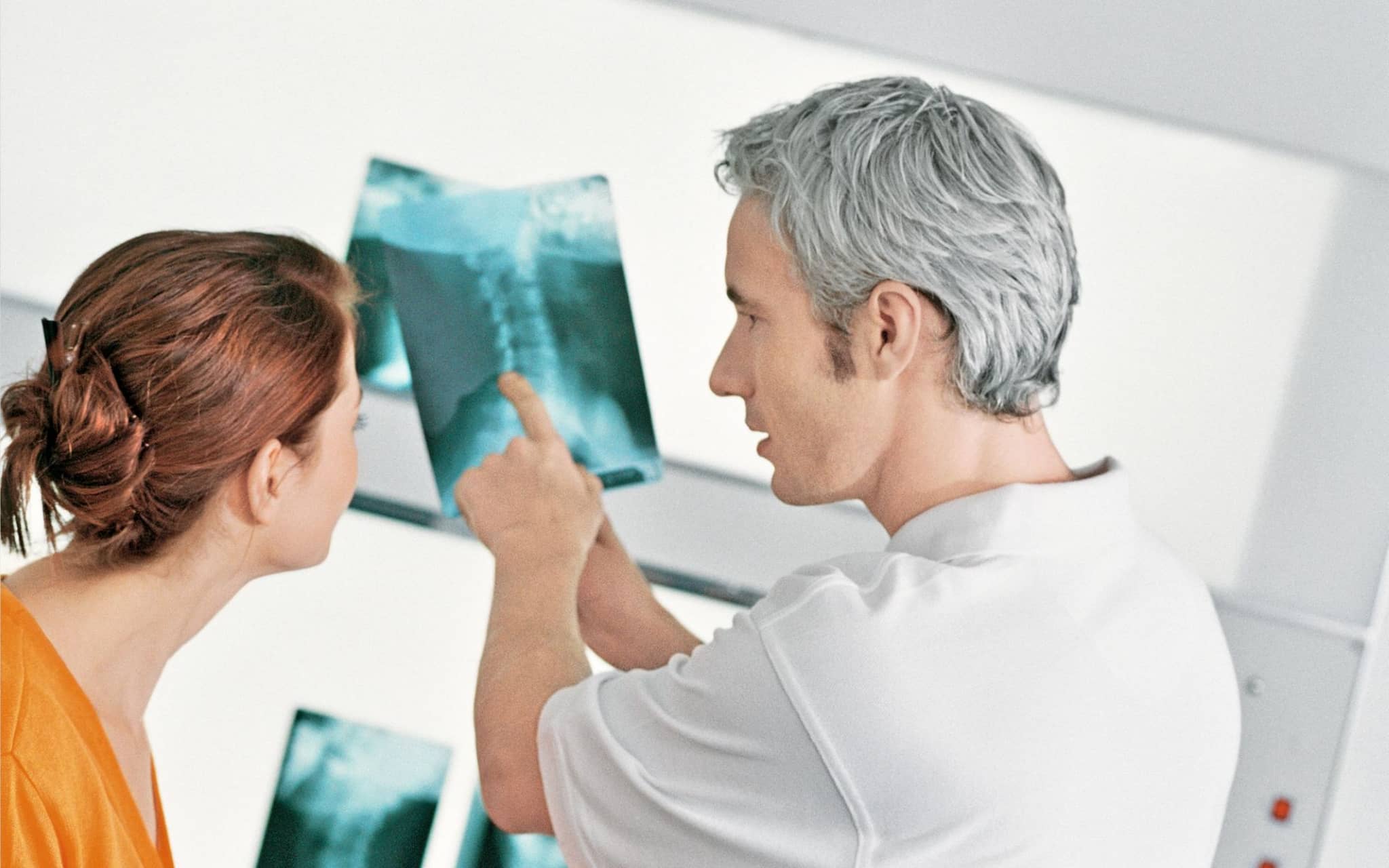 Arzt erklärt einer Patientin das Röntgenbild, das sie später in ihrer elektronischen Patientenakte finden wird.