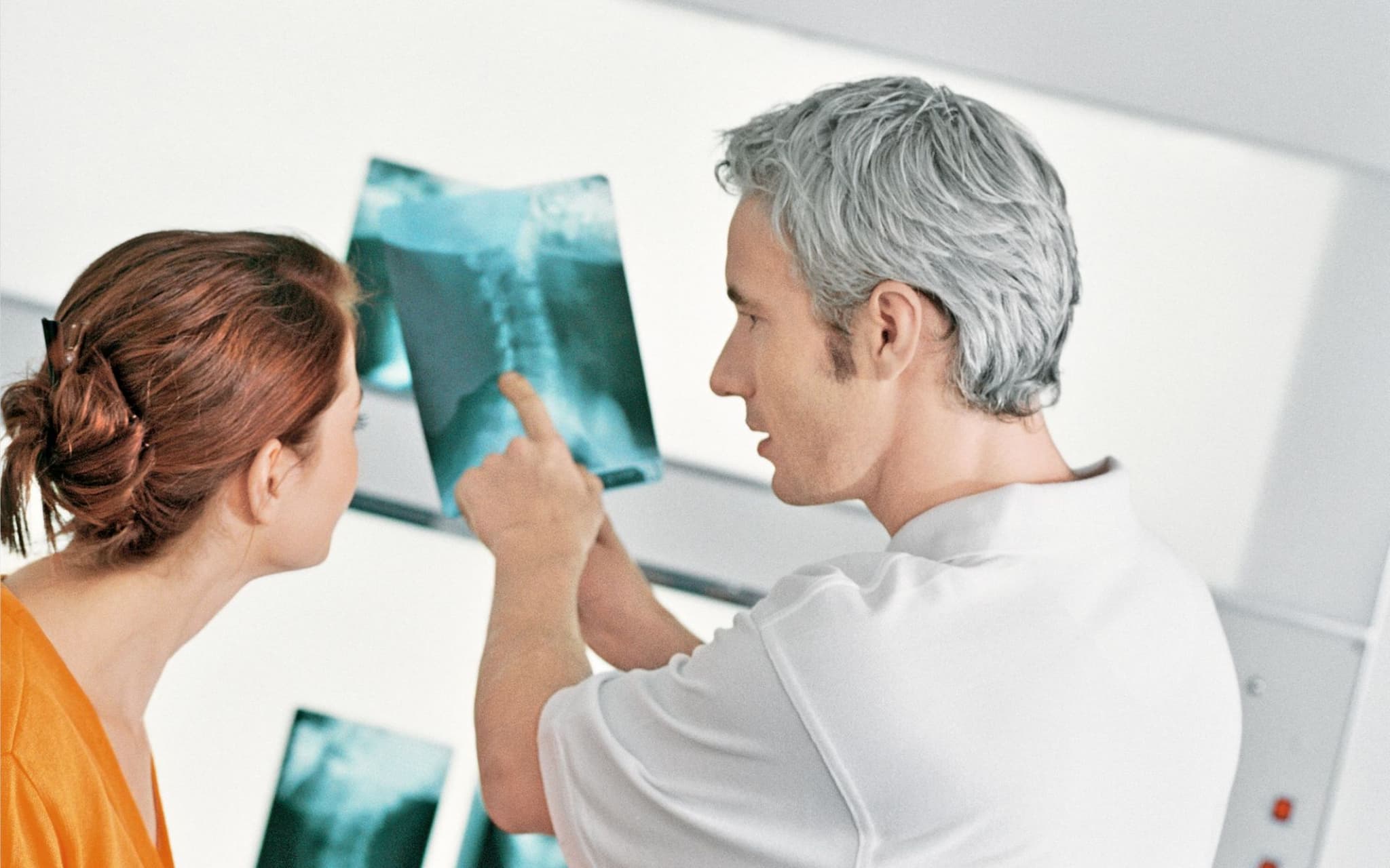 Arzt erklärt einer Patientin das Röntgenbild, das sie später in ihrer elektronischen Patientenakte finden wird.