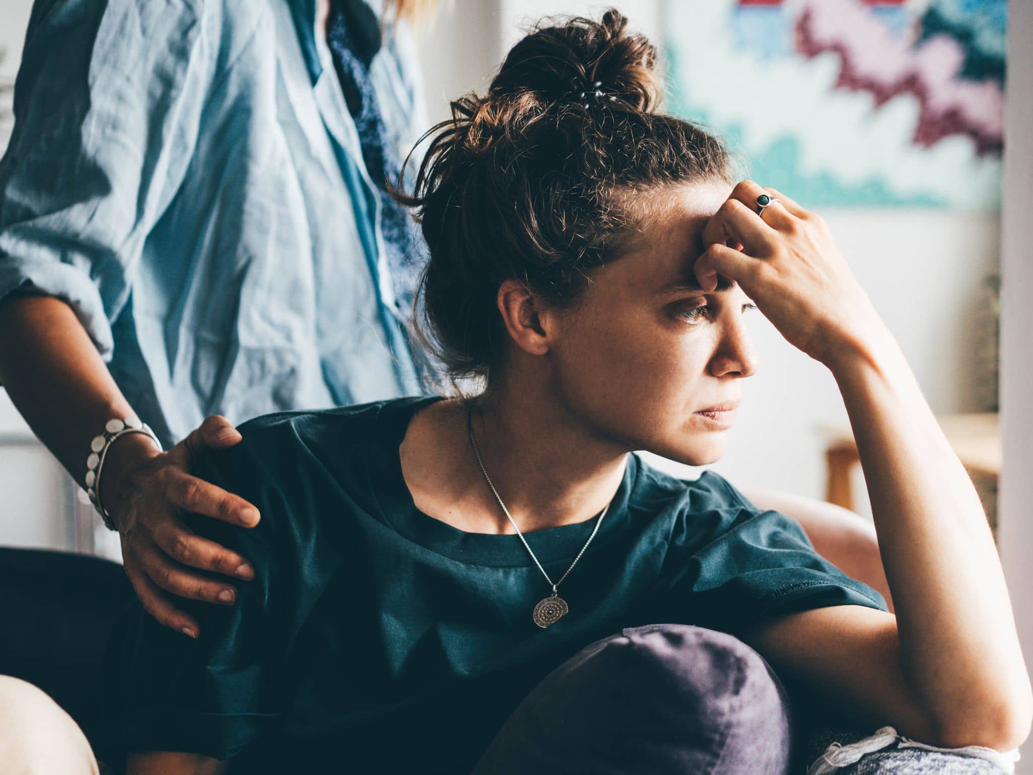 Stressoren: Eine Frau stützt ihren Kopf ab, ein Mann legt seine Hand auf die Schulter