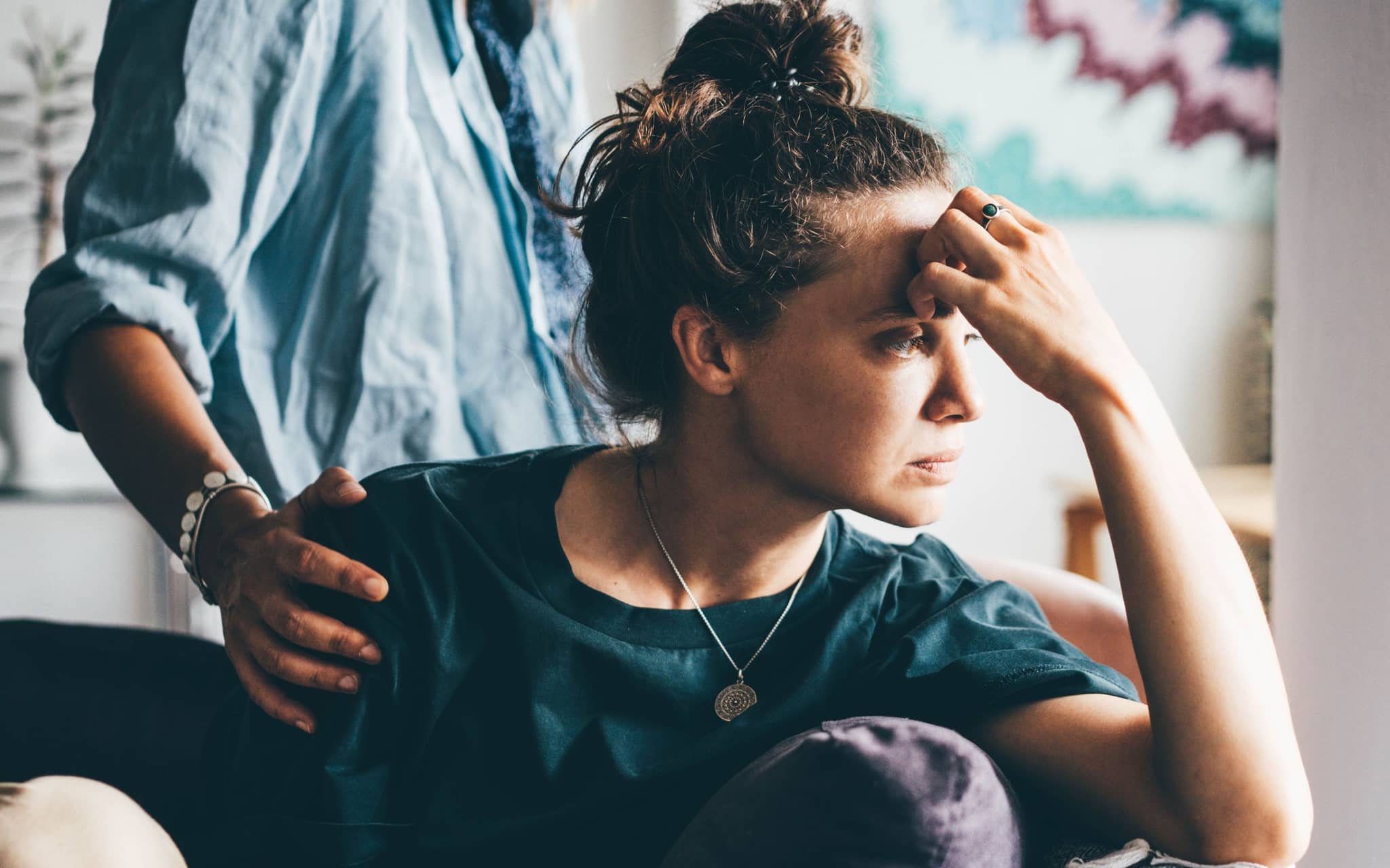 Stressoren: Eine Frau stützt ihren Kopf ab, ein Mann legt seine Hand auf die Schulter