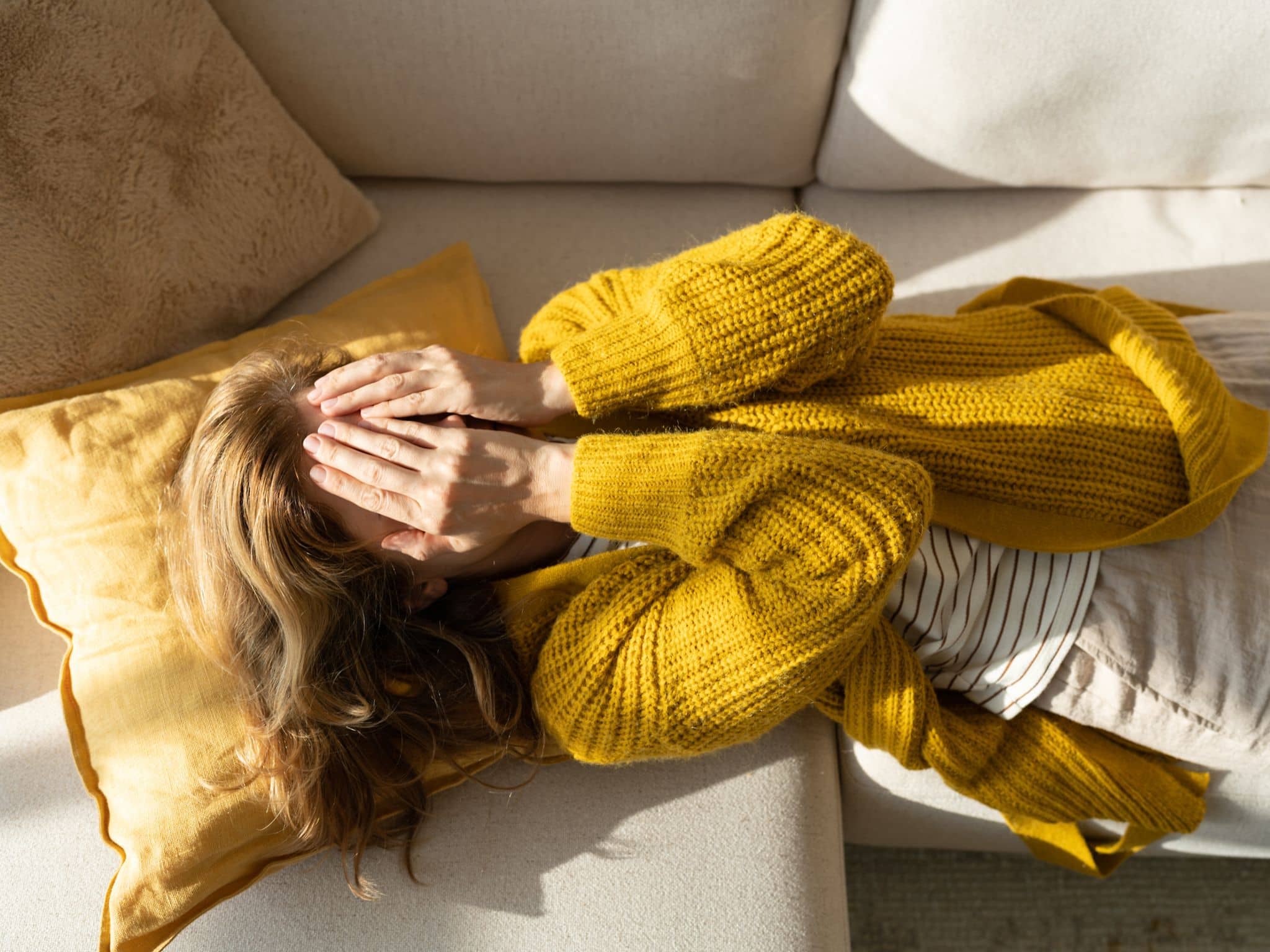 Stress - Warnsignale des Körpers: Eine Frau liegt erschöpft auf ihrem Bett