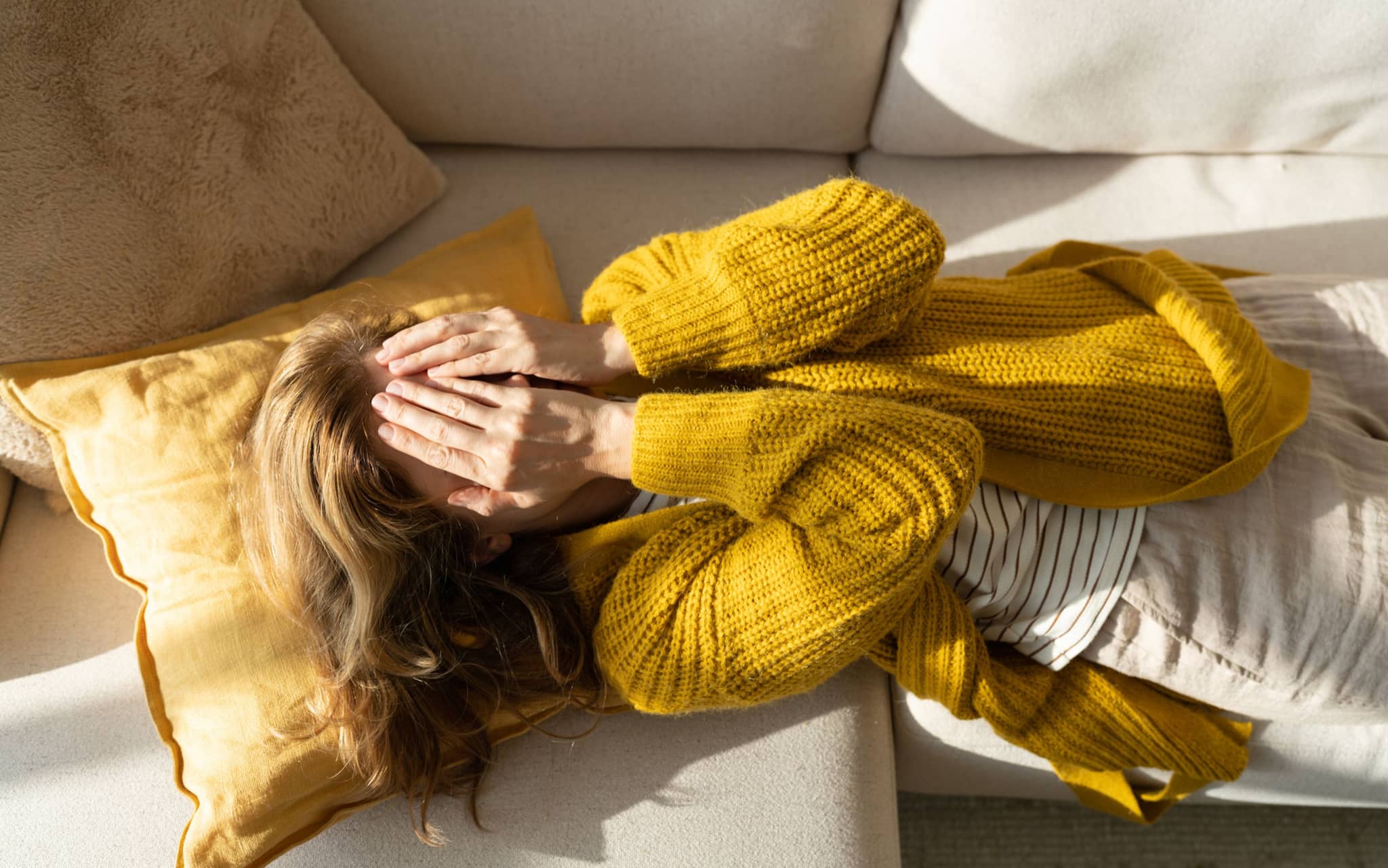 Stress - Warnsignale des Körpers: Eine Frau liegt erschöpft auf ihrem Bett