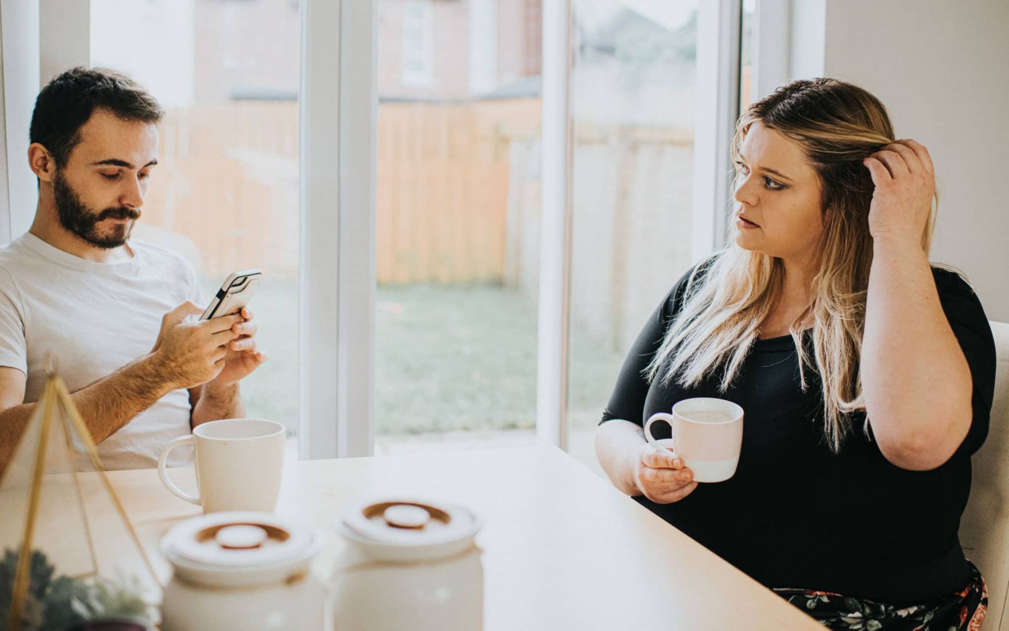 Phubbing - eine Frau ist genervt, weil der Partner ständig am Handy hängt.