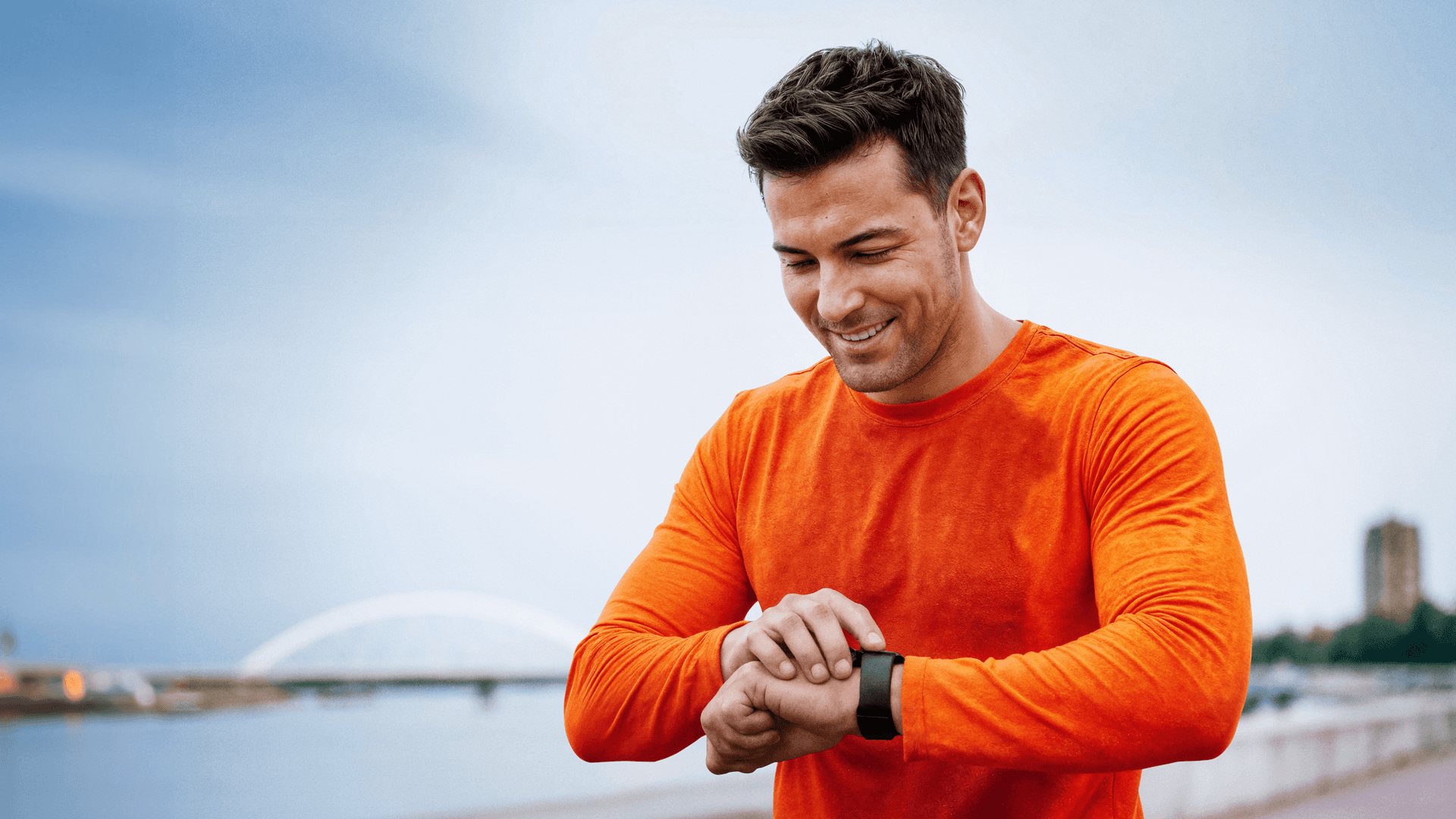 Ein Mann pausiert das Joggen und checkt seinen Fitnesstracker