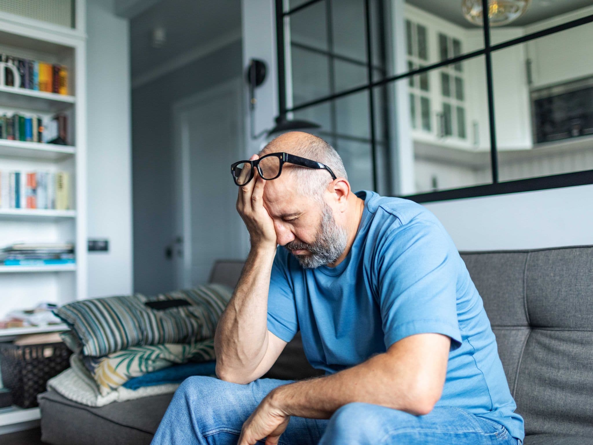 Altersdepressionen: Ein älterer Mann sitzt auf einem Sofa und denkt nach