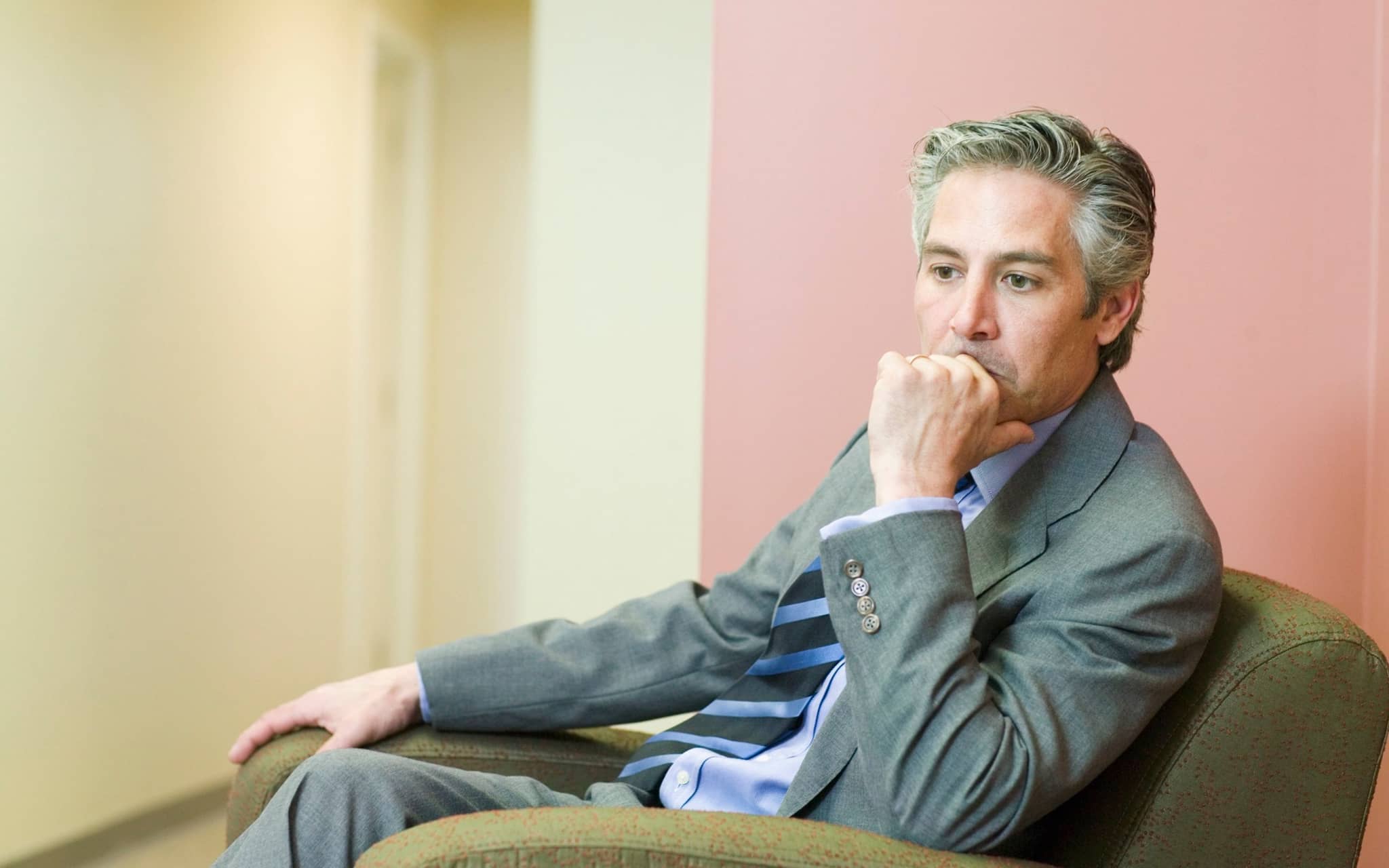 Posttraumatische Belastungsstörung: Ein älterer Herr im Anzug sitzt in einem Sexel und guckt traurig-depressiv