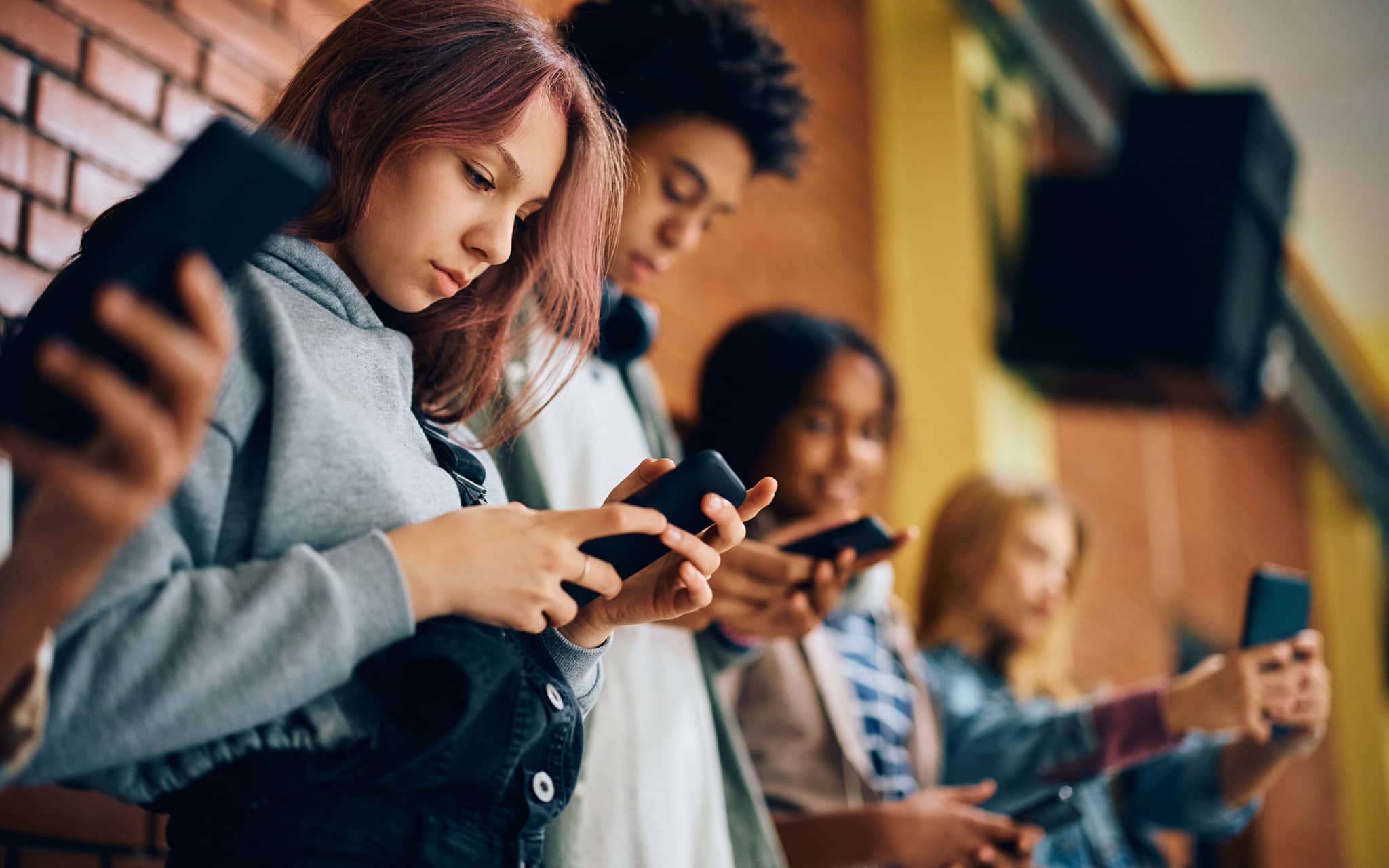 Gruppe von Jugendlichen starrt in der Schule auf ihre Smartphones
