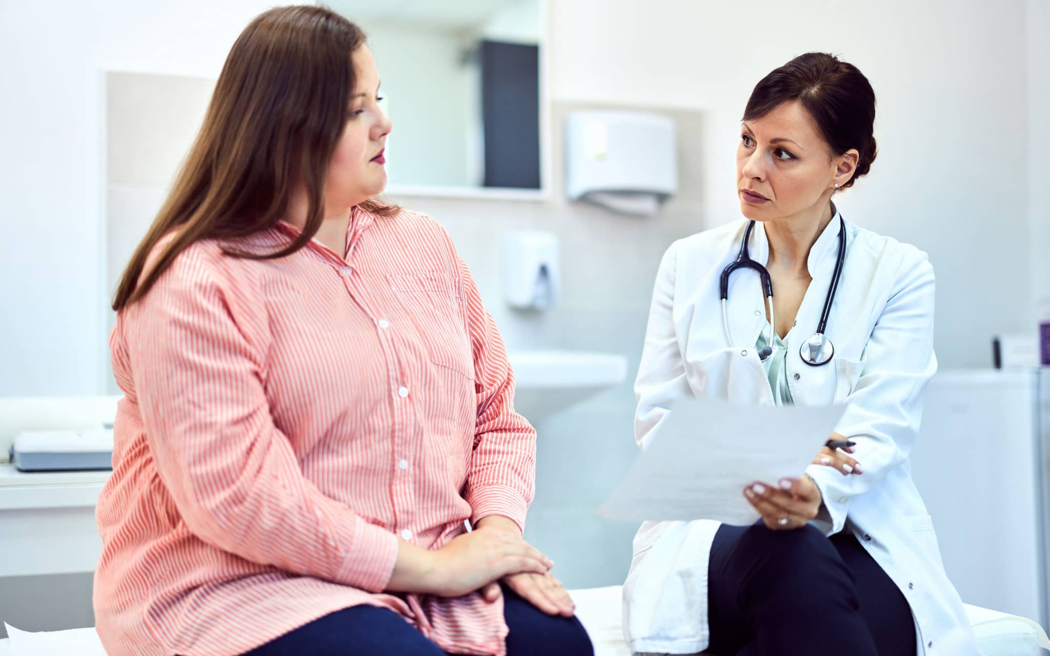 Lipödem-OP: Eine Frau mit Lipödem sitzt mit einer Ärztin im Behandlungsraum eines Krankenhauses