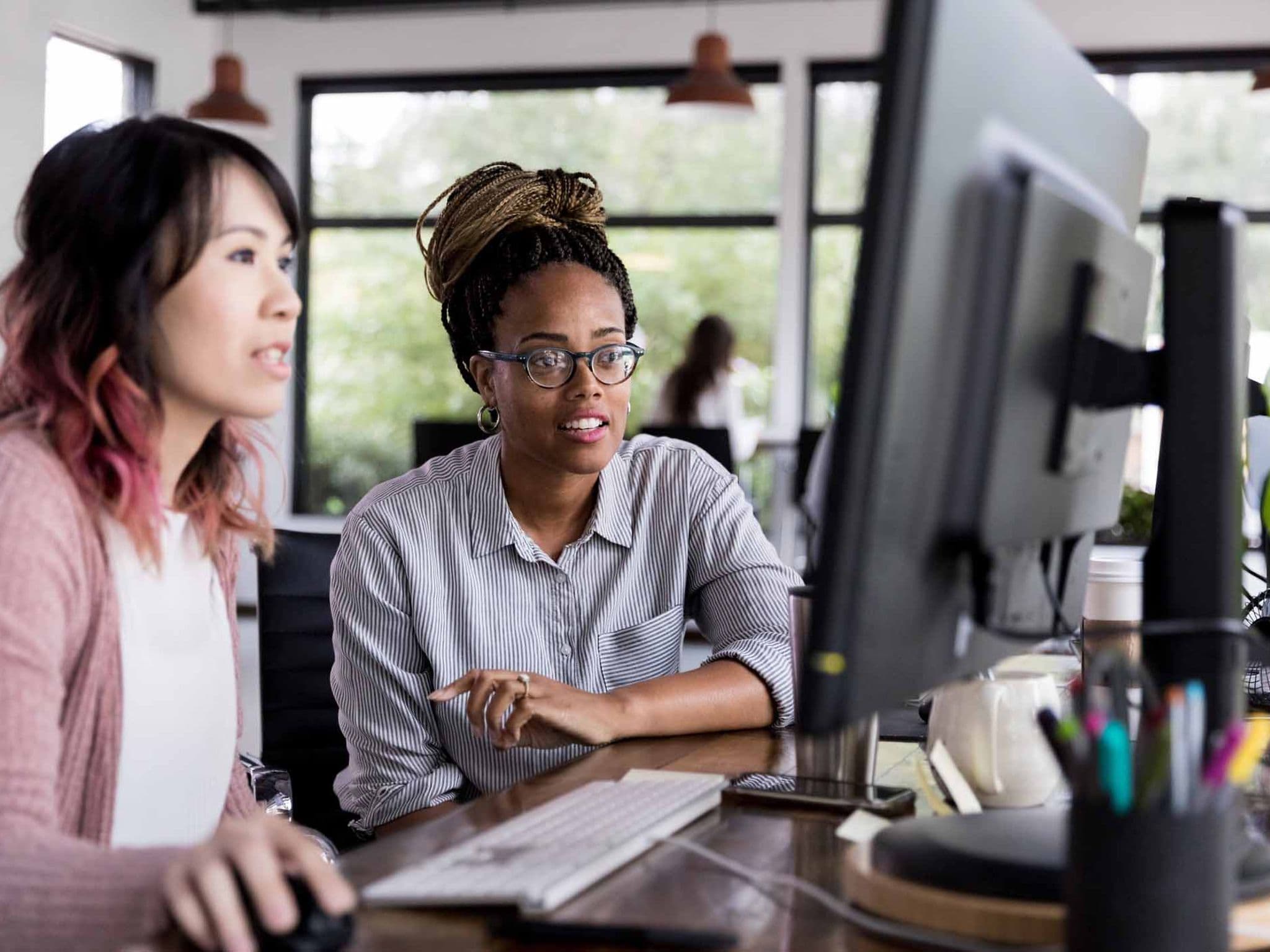 Säumniszuschläge vermeiden: Zwei Kolleginnen schauen auf einen Computer und planen, die Beitragsnachweise zu übermitteln.