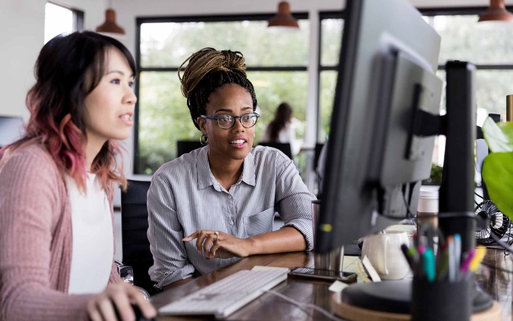 Säumniszuschläge vermeiden: Zwei Kolleginnen schauen auf einen Computer und planen, die Beitragsnachweise zu übermitteln.