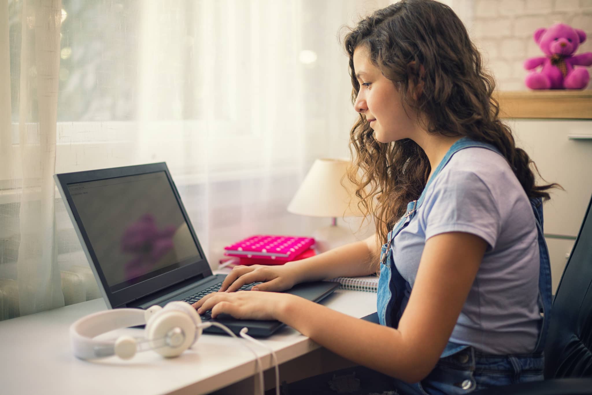 Jugendliches Mädchen sitzt vorm Computer und freut sich