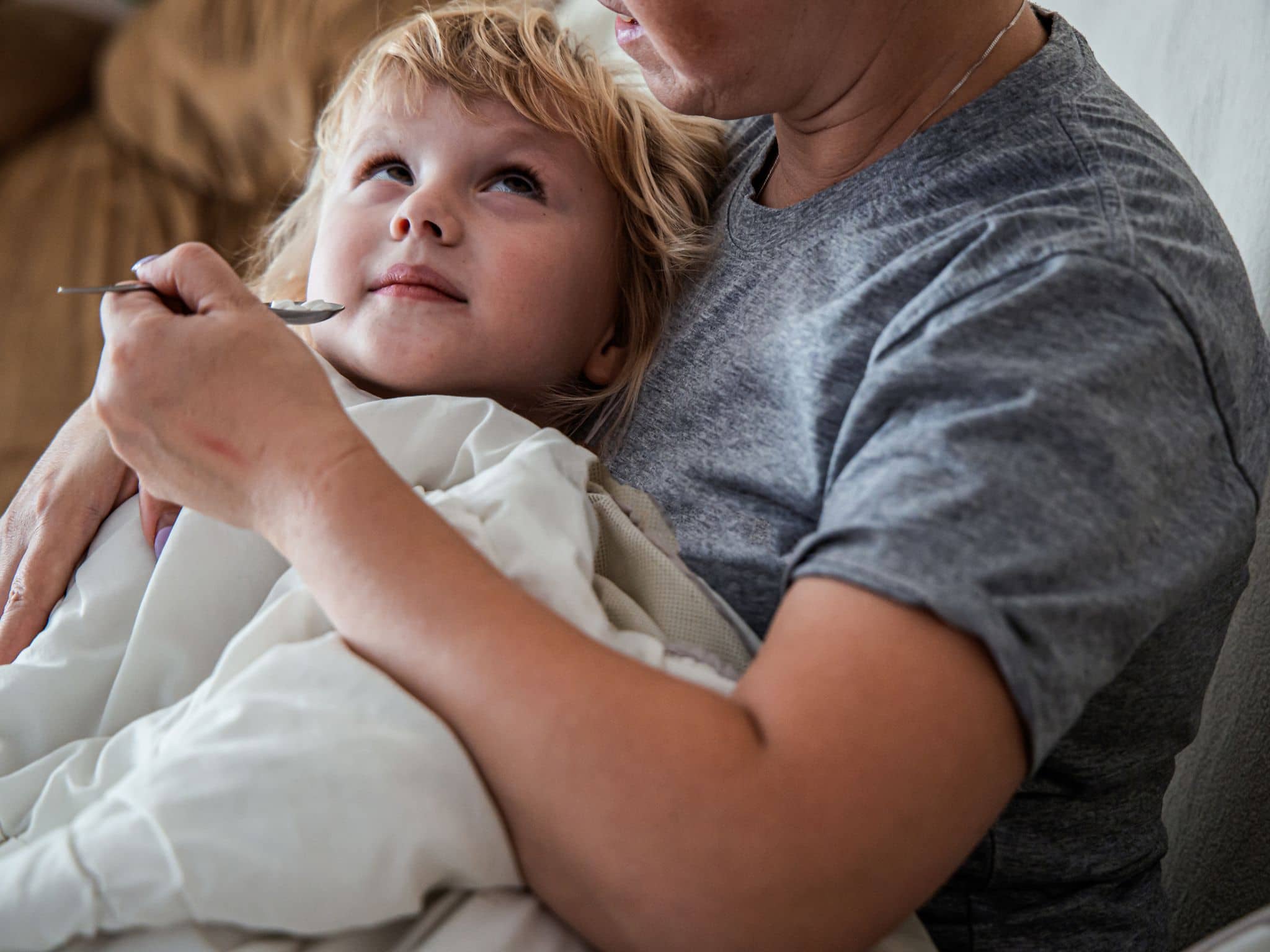 Schmerzmittel für Kinder: Ein kleines Mädchen bekommt einen Teelöffel mit Medizin