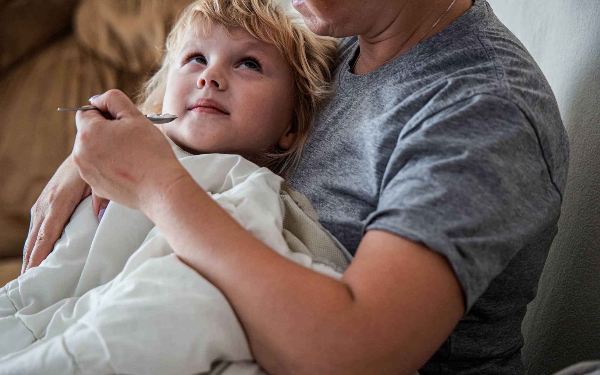 Schmerzmittel für Kinder: Ein kleines Mädchen bekommt einen Teelöffel mit Medizin