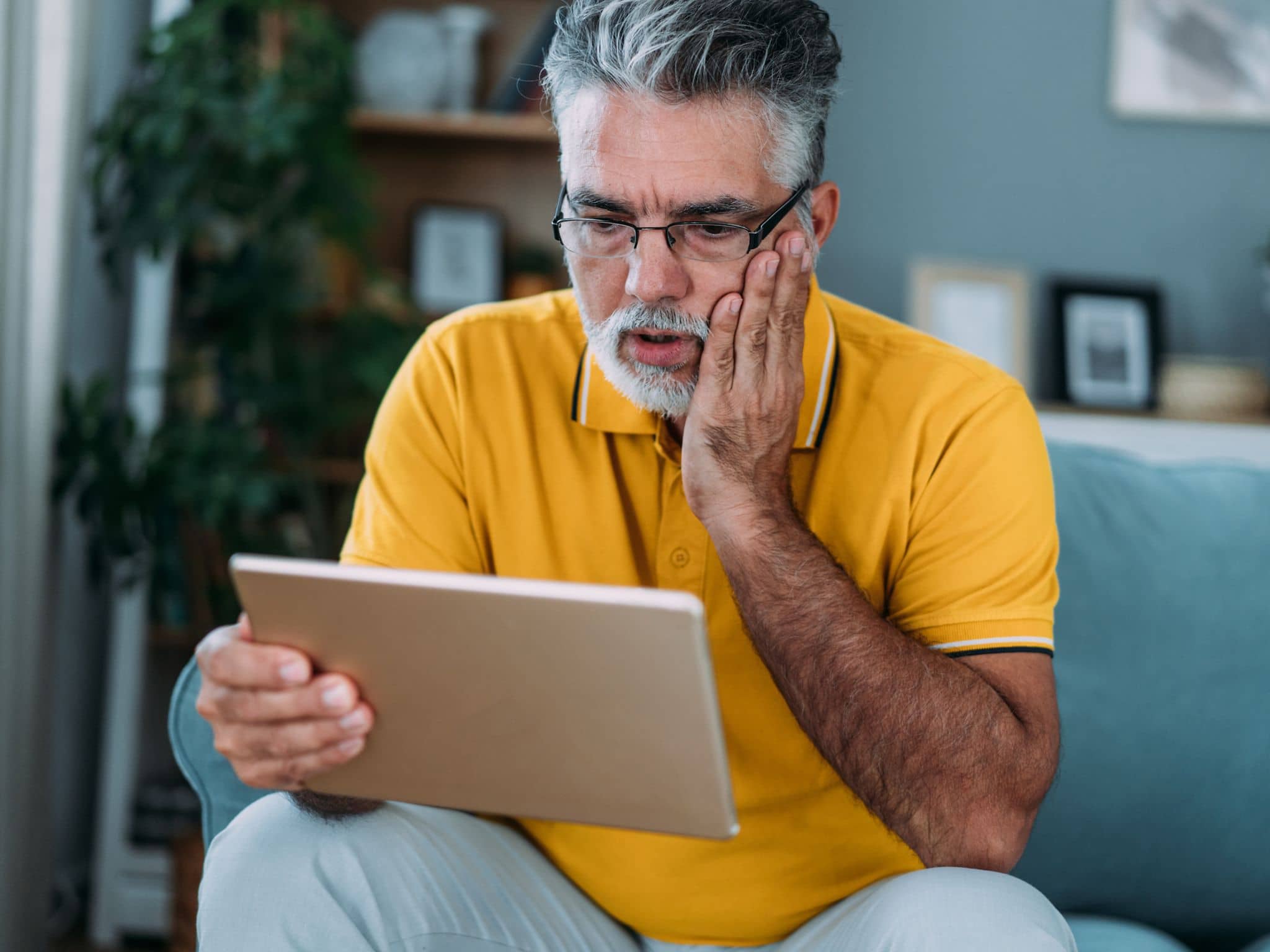 Hypochondrie: Ein Mann sitzt auf einem Sofa und recherchiert auf einem Tablet