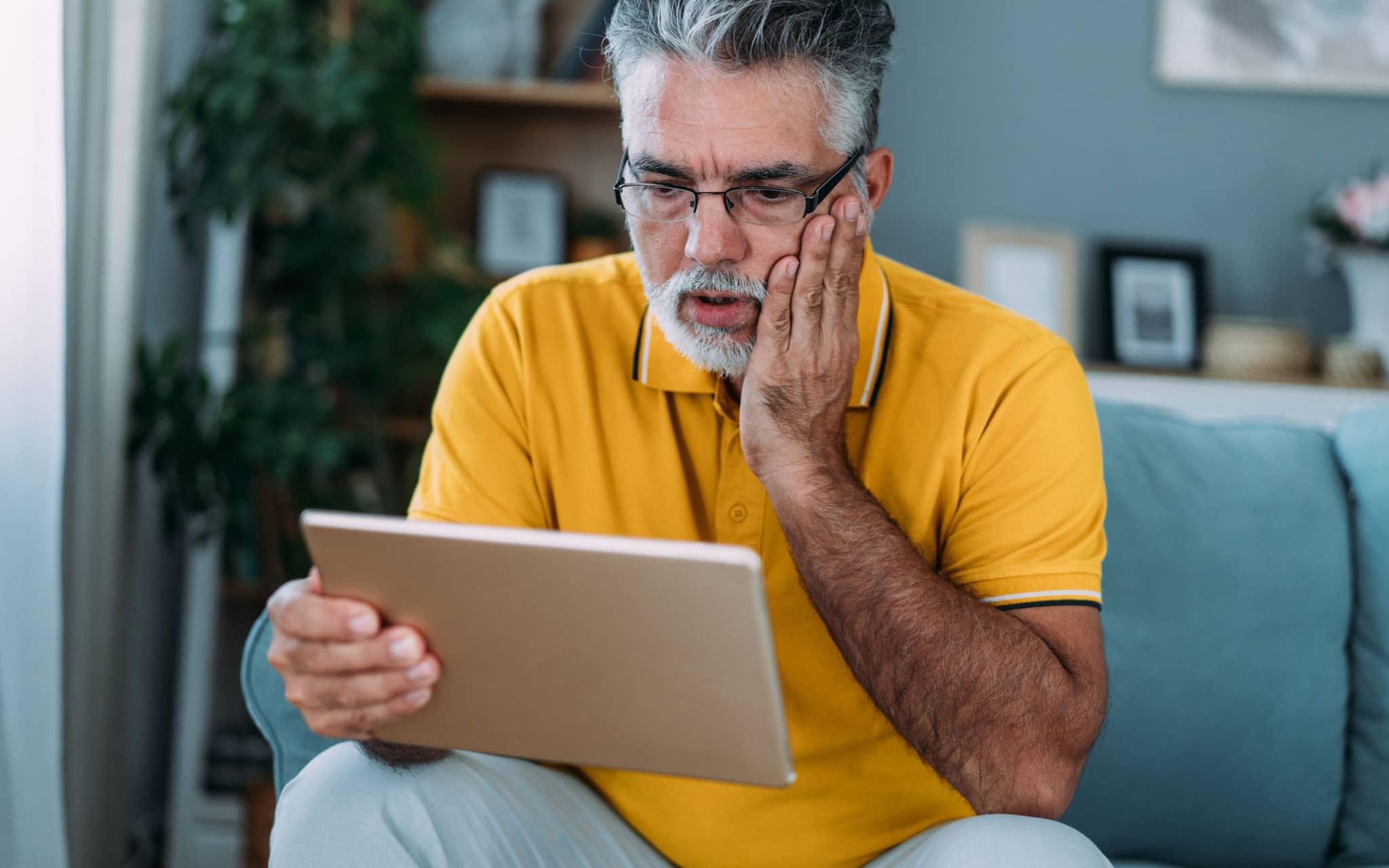 Hypochondrie: Ein Mann sitzt auf einem Sofa und recherchiert auf einem Tablet
