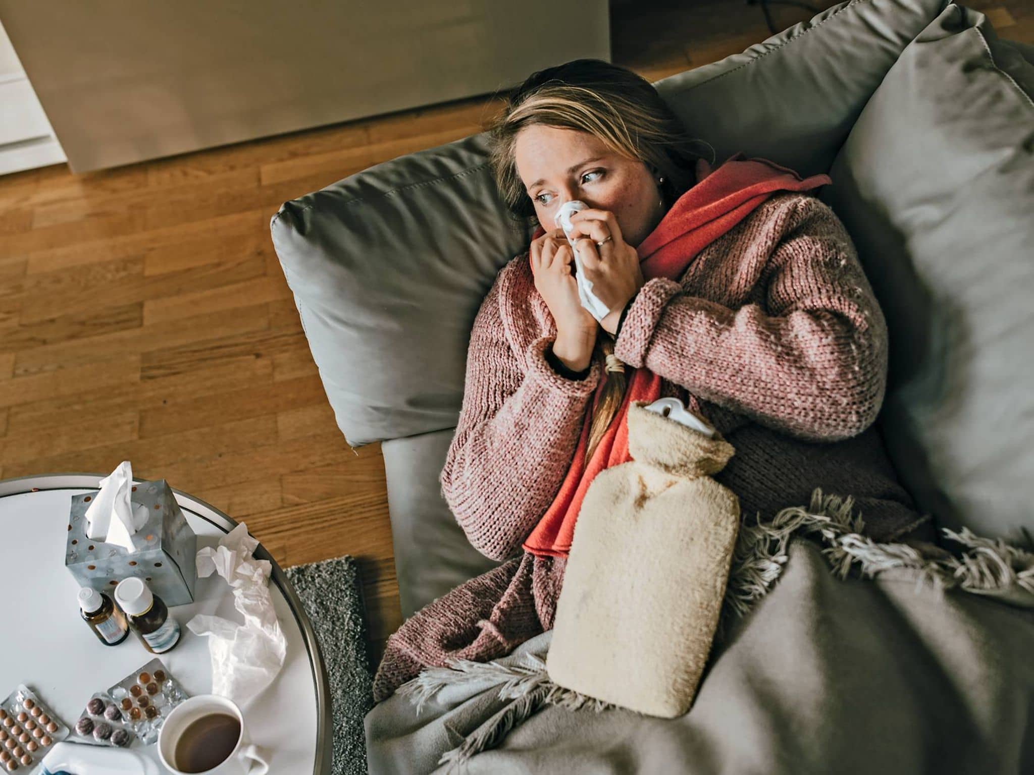 Eine Frau mit Erkältung oder Grippe liegt auf dem Sofa um sich zu erholen.