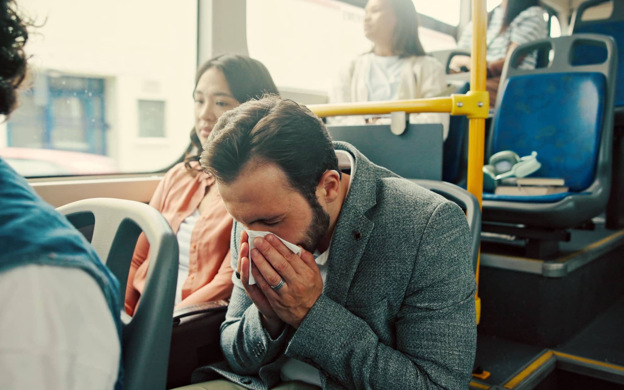 Ein Mann ist erkältet im Bus und fragt sich, wie lange er mit Erkältung wohl ansteckend ist.
