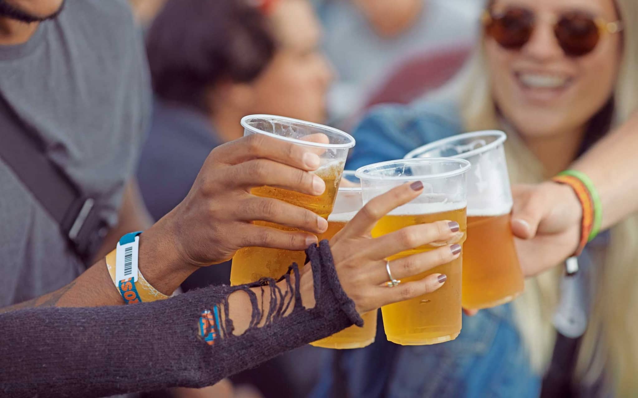 Nahaufnahme von Händen, die mit Bechern voll Bier anstoßen