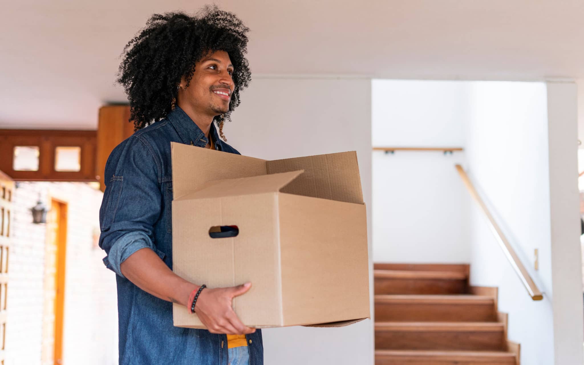 What you should do after arriving in Germany: Young man entering his new house with boxes.