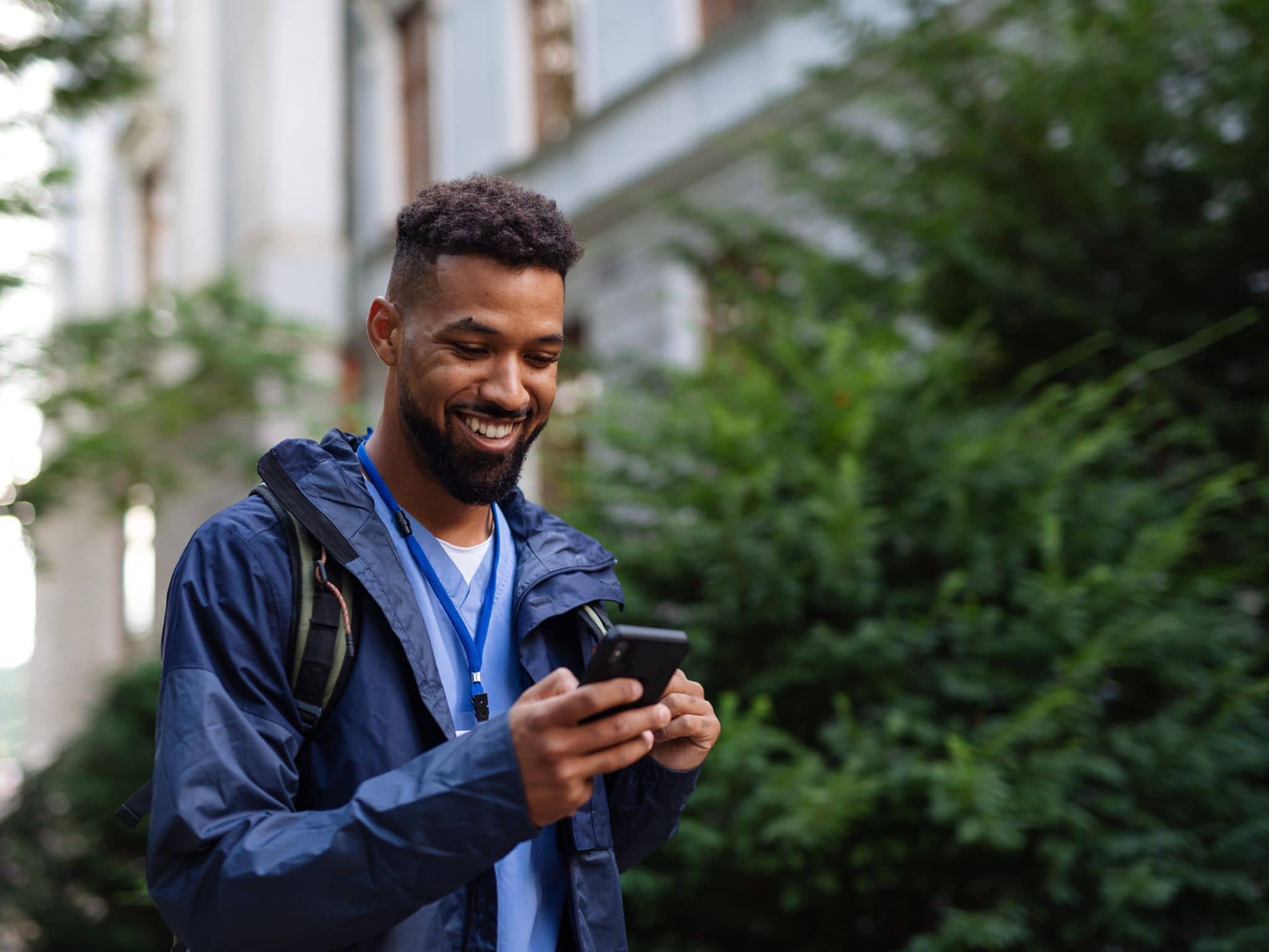 DAK App: Man outdoors in street using a phone, smiling.