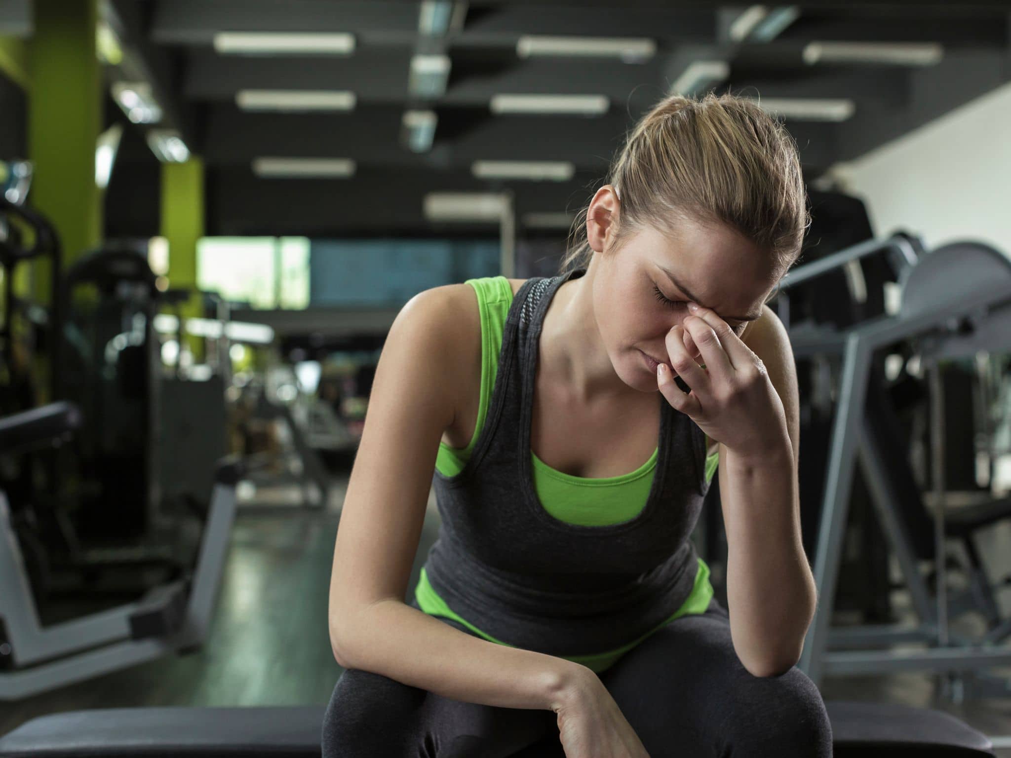 Sportlerin greift sich erschöpft an den Nasenrücken