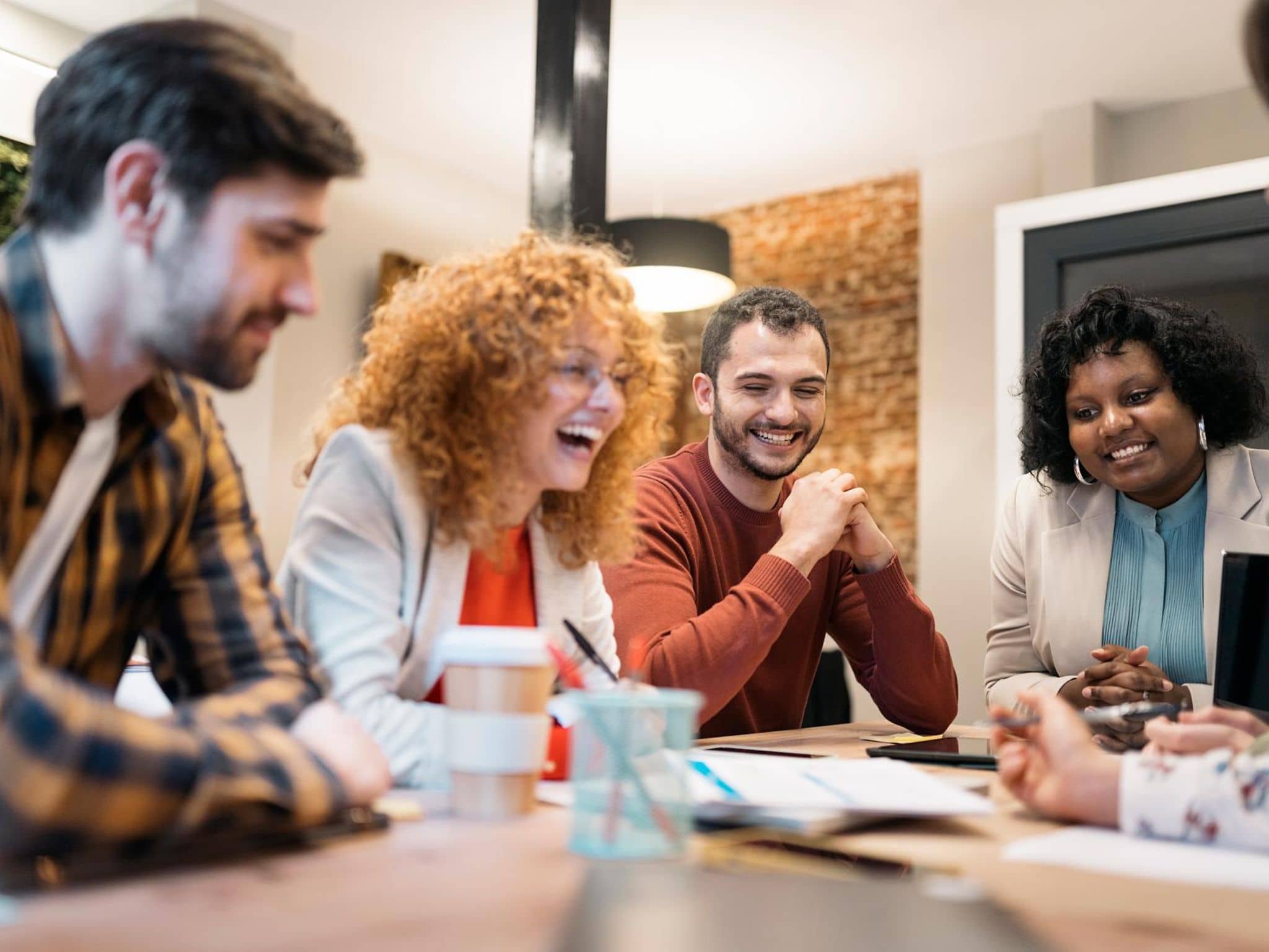 Symbolbild für Online-Vortrag "Gesunde Zusammenarbeit stärken". Kollegen lachen miteinander.